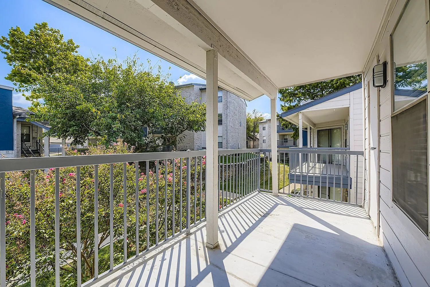 Covered balcony, metal railing, tree views, building exteriors