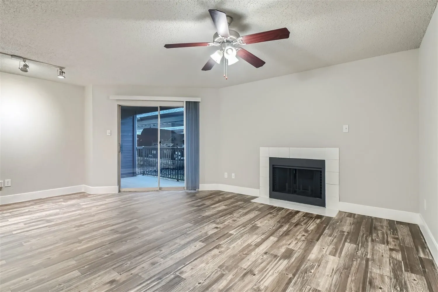 A2 Gold living room, fireplace, ceiling fan, sliding glass door, wood-style plank flooring