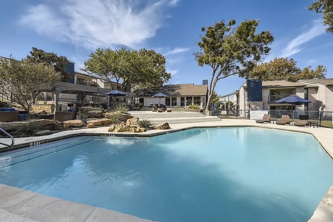Community pool, rock landscaping, mature trees, building exteriors, pool deck