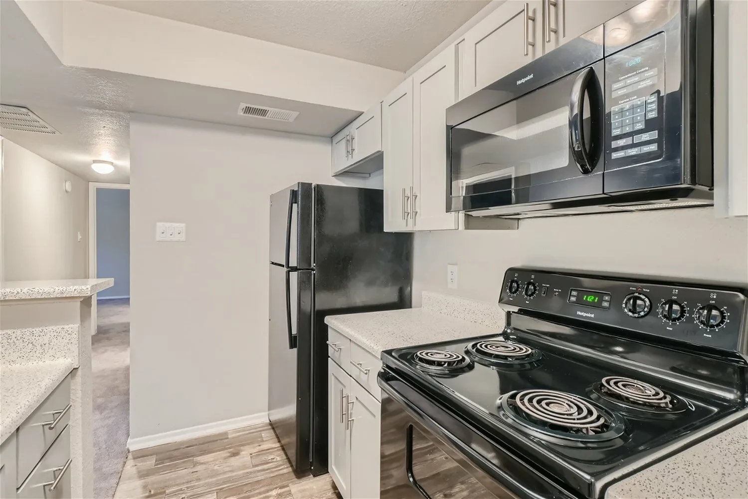 Kitchen, black appliances, electric coil range, over-range microwave, white cabinetry