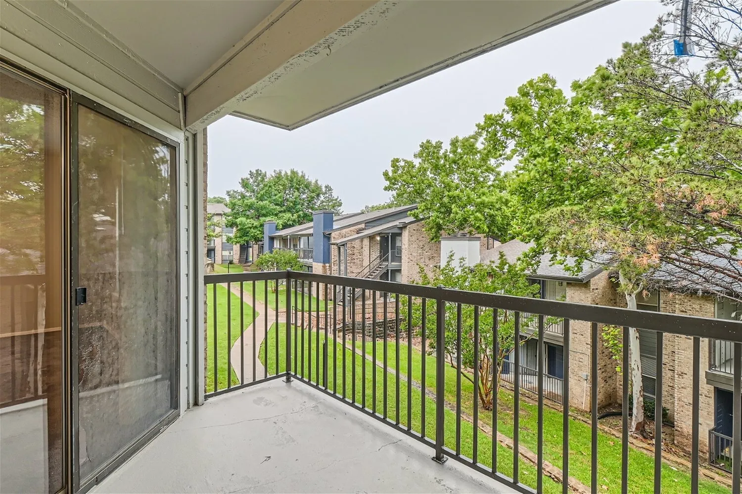 Balcony, metal railing, landscaped grounds, mature trees