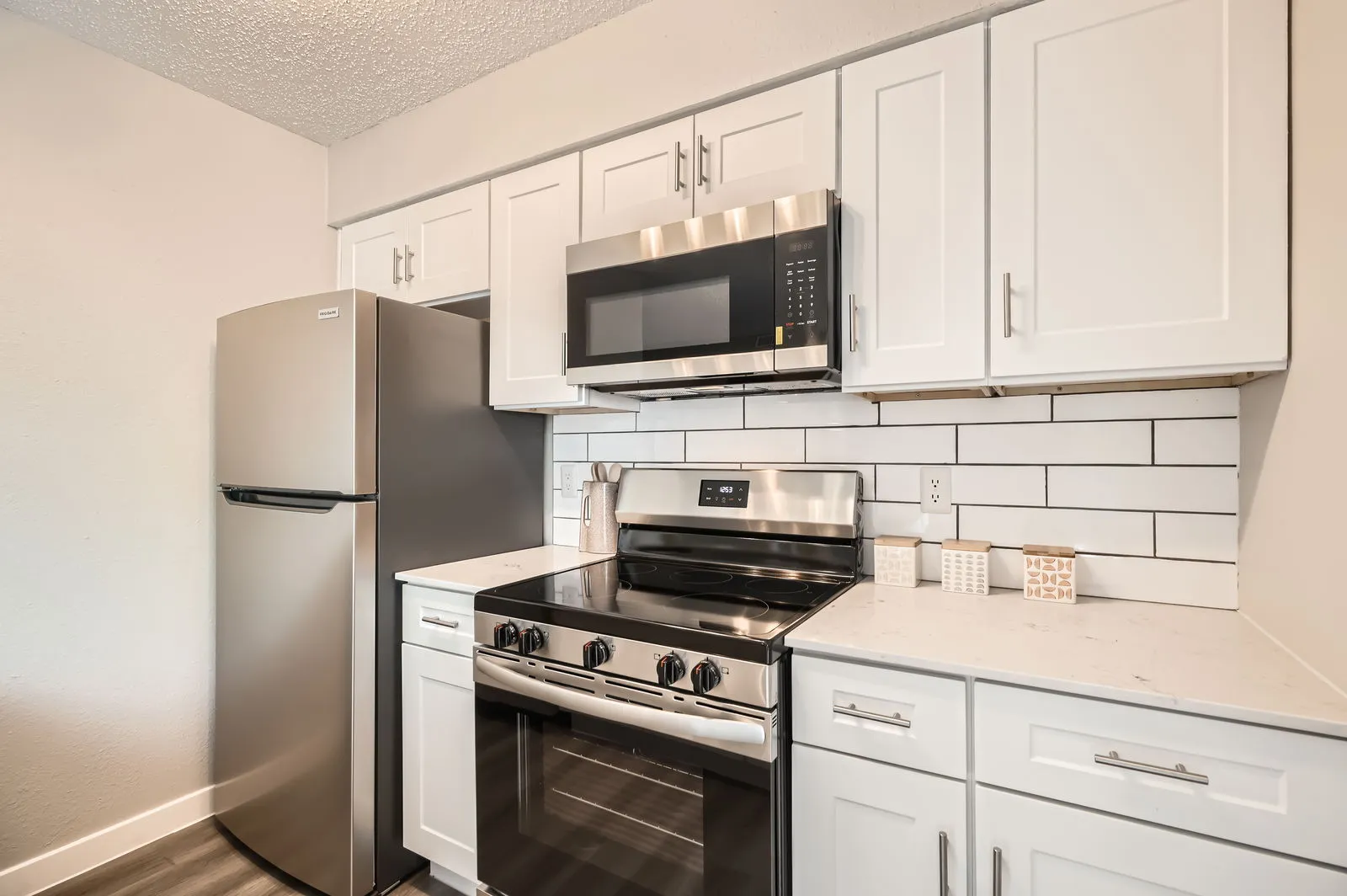 Kitchen with white cabinetry, stainless steel appliances, and subway tile backsplash