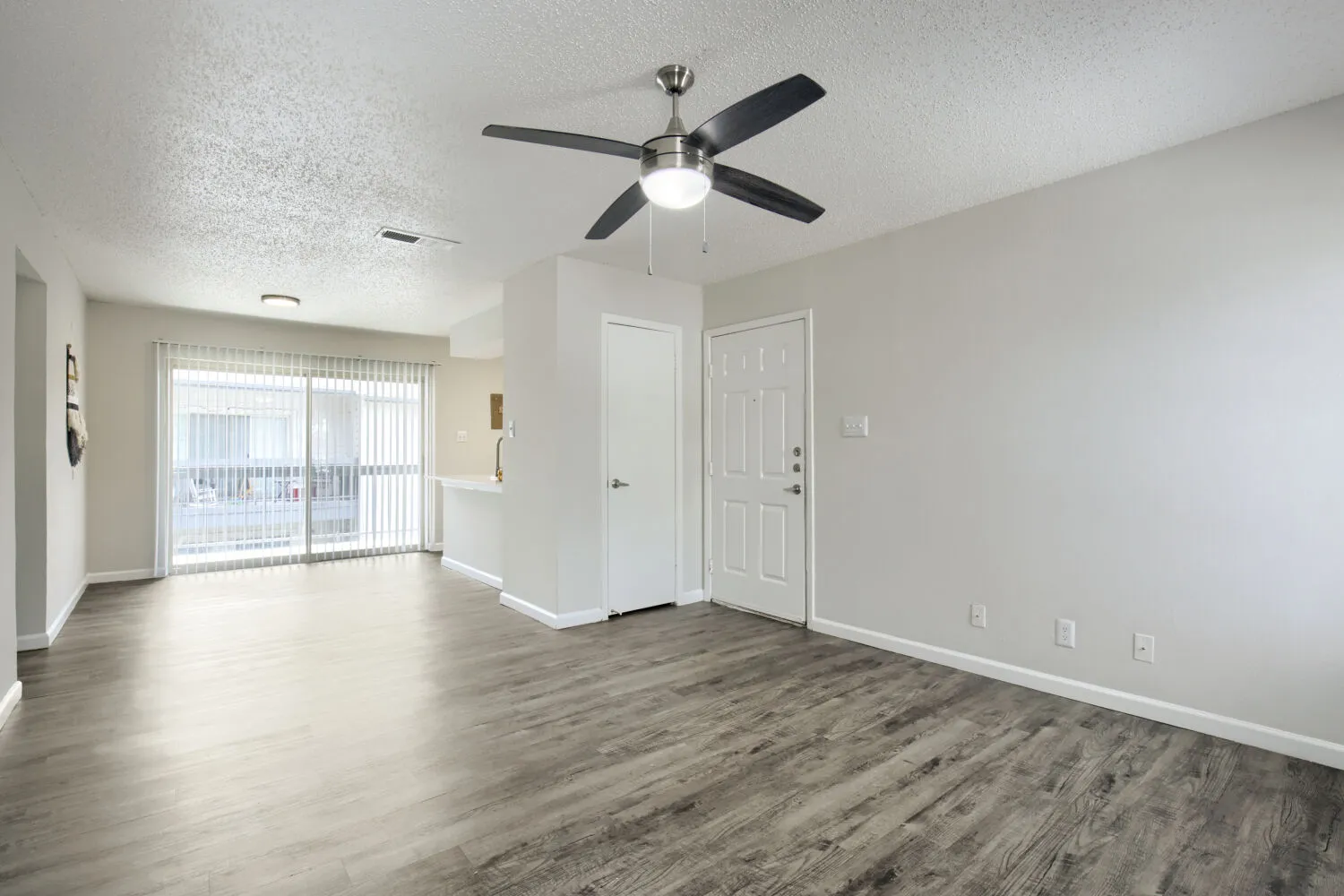 Living room with sliding glass door and view into kitchen