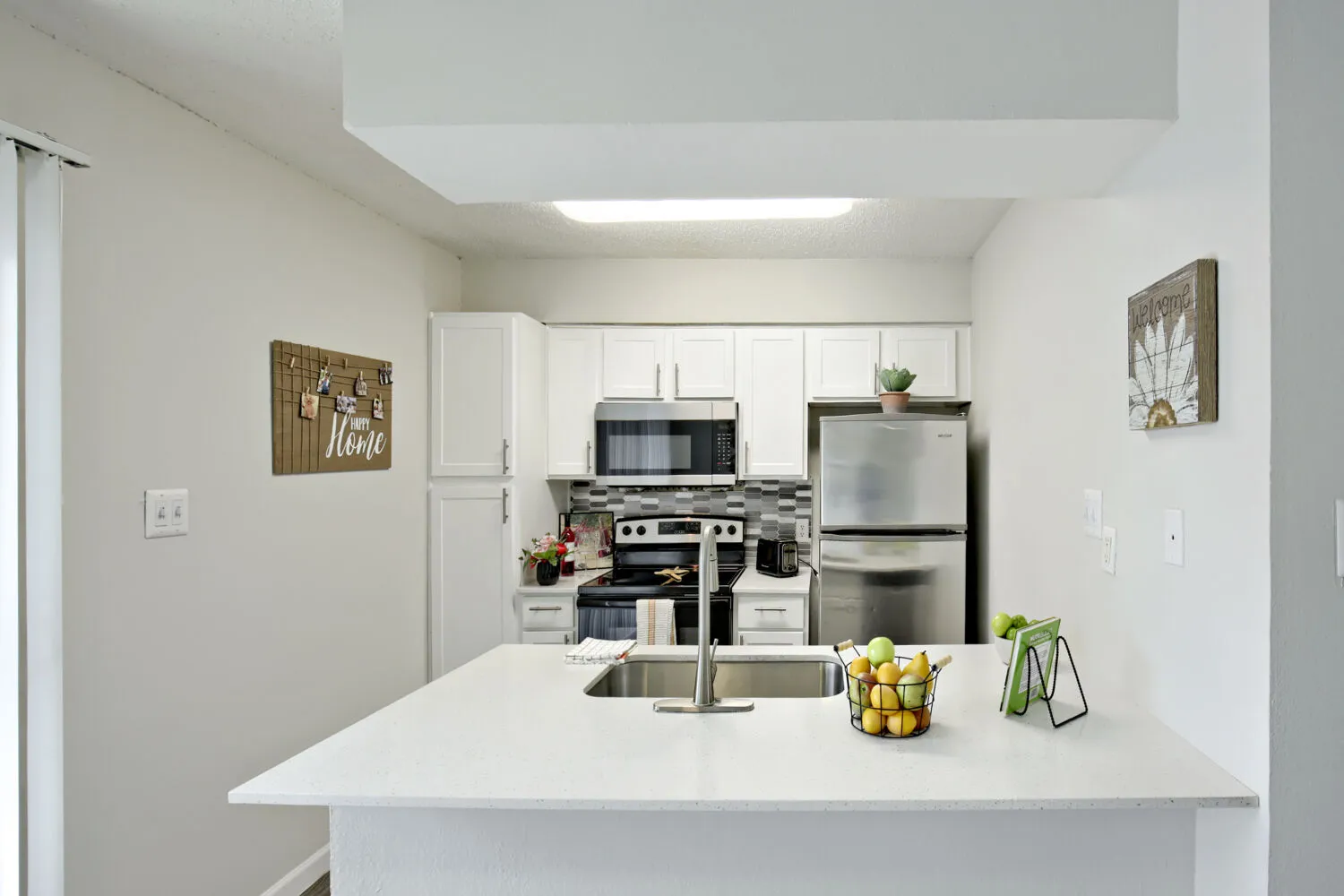 Kitchen with white cabinetry, stainless steel appliances, and tile backsplash