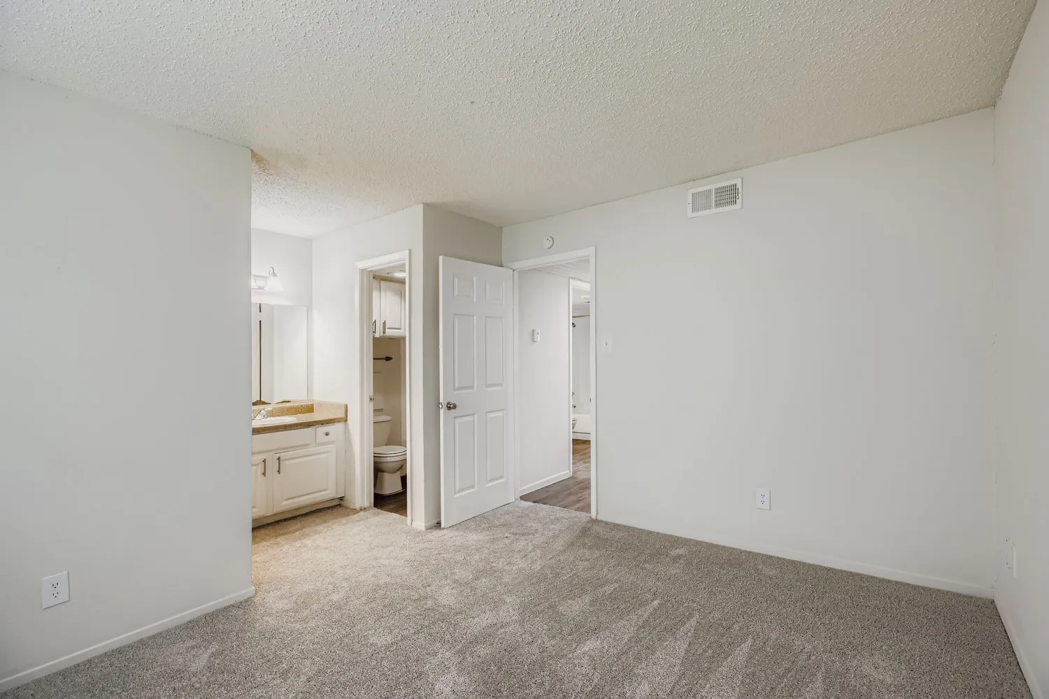 Primary bedroom with view into ensuite bathroom and hallway