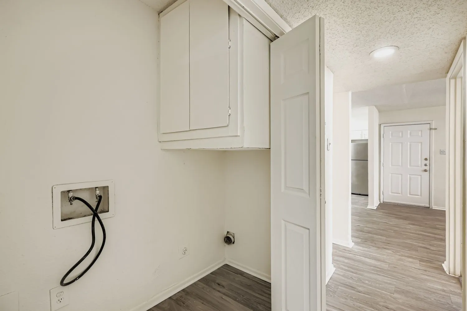 Laundry closet with cabinet storage and hallway view into kitchen