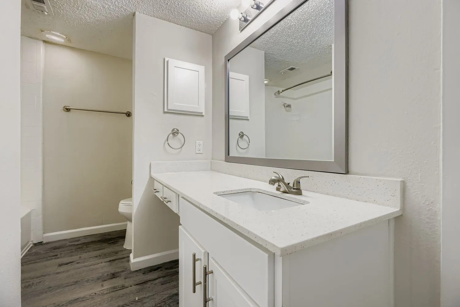 Primary bathroom vanity with quartz-style countertop and framed mirror