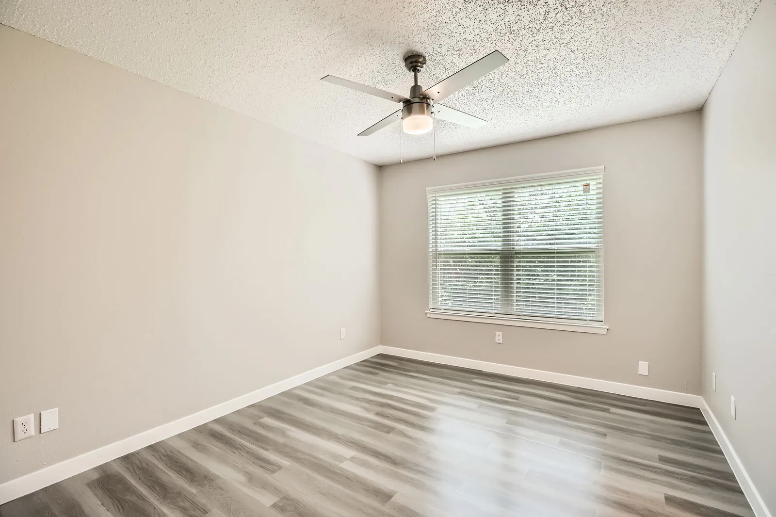 Primary bedroom with wood-style plank flooring and window