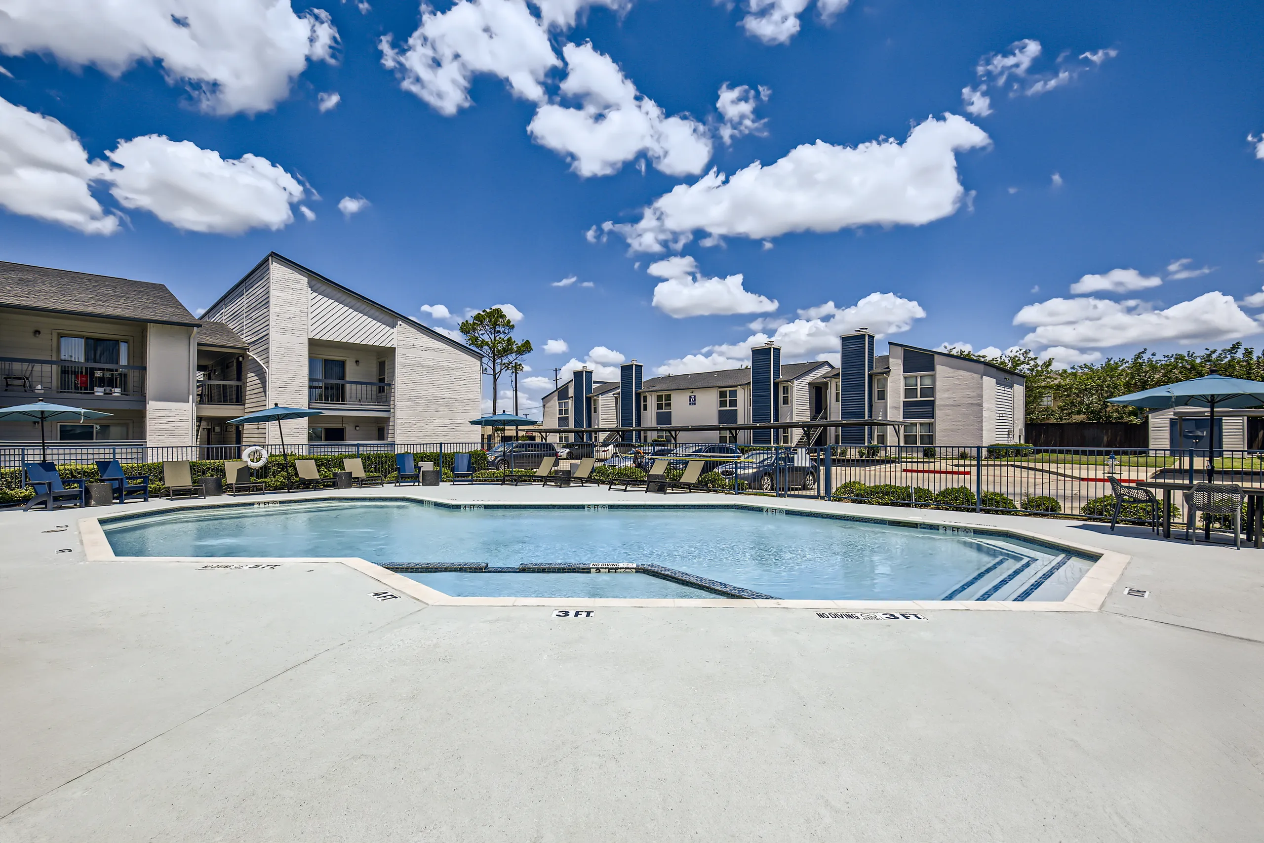 Outdoor swimming pool surrounded by lounge chairs and umbrellas