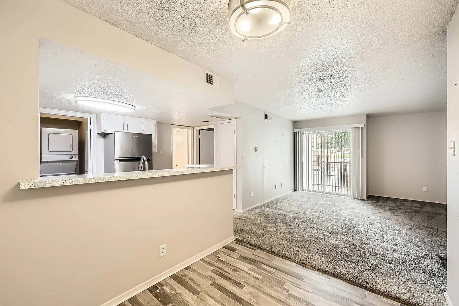 Open concept living space, wood-style plank flooring, white cabinetry, stainless appliances, quartz countertops