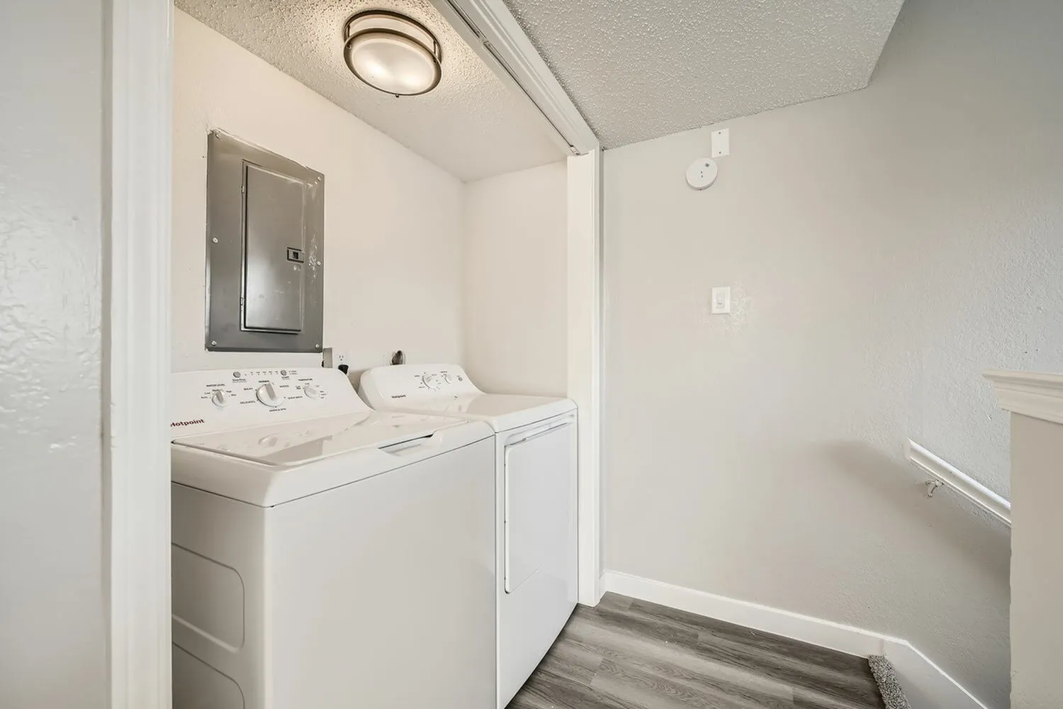 Laundry room, white washer and dryer, wood-style plank flooring, ceiling fixture
