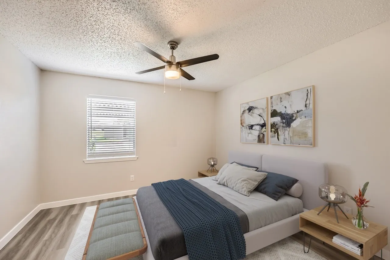 Primary bedroom, wood-style plank flooring, gray bedding, ceiling fan, window