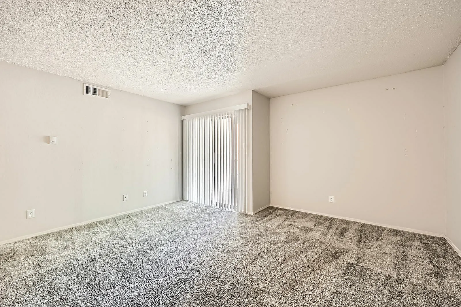 Living room, carpet flooring, vertical blinds, neutral walls, textured ceiling