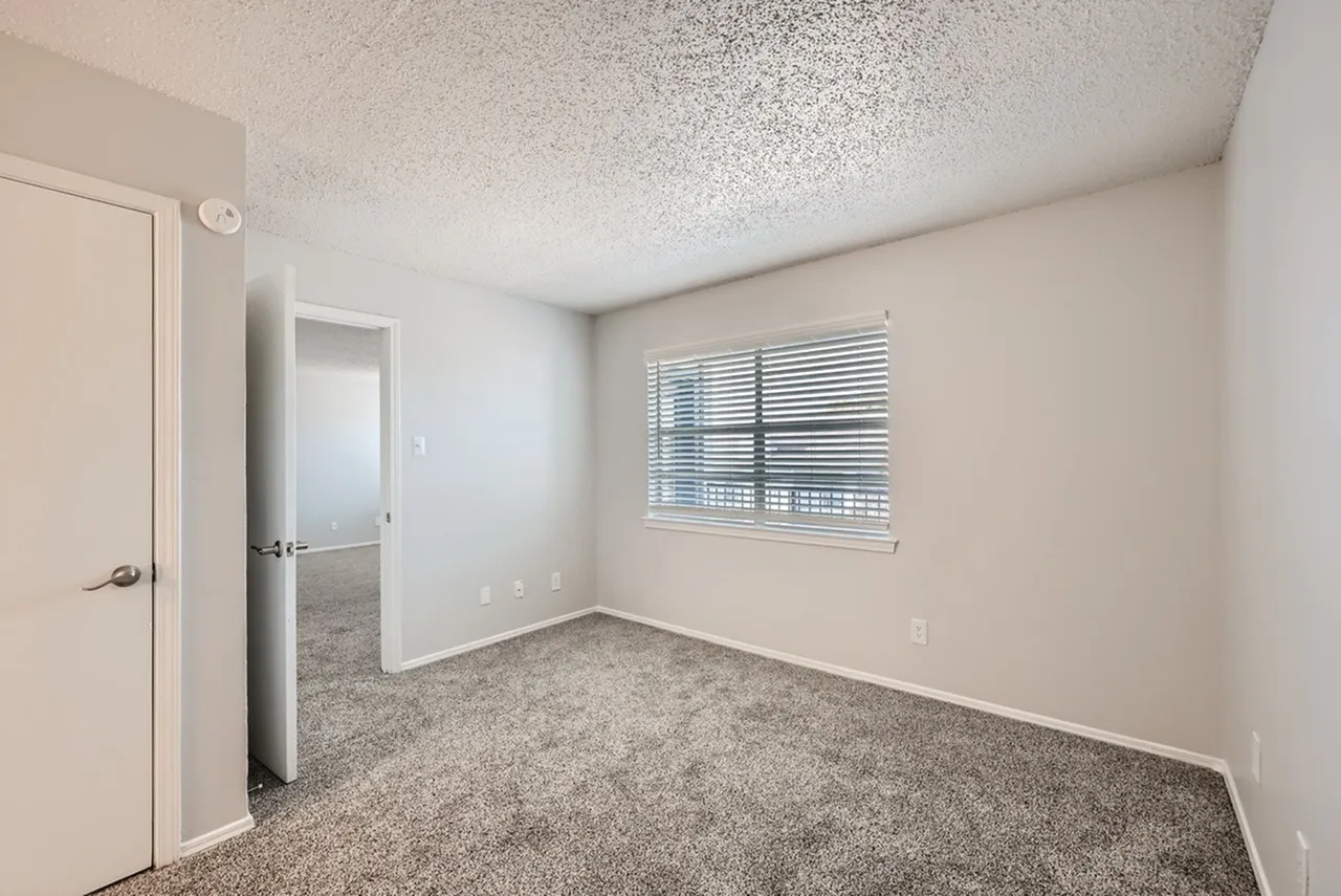 Bedroom, gray carpet flooring, white interior doors, window with blinds