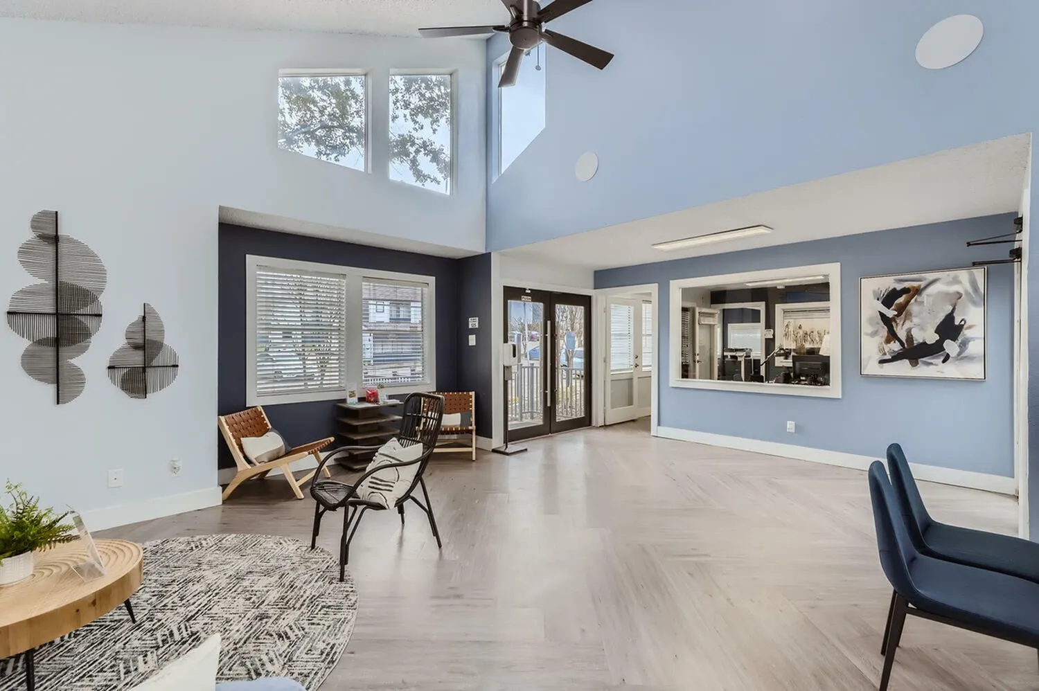 Open living area, wood-style plank flooring, blue accent walls, ceiling fan, geometric wall art