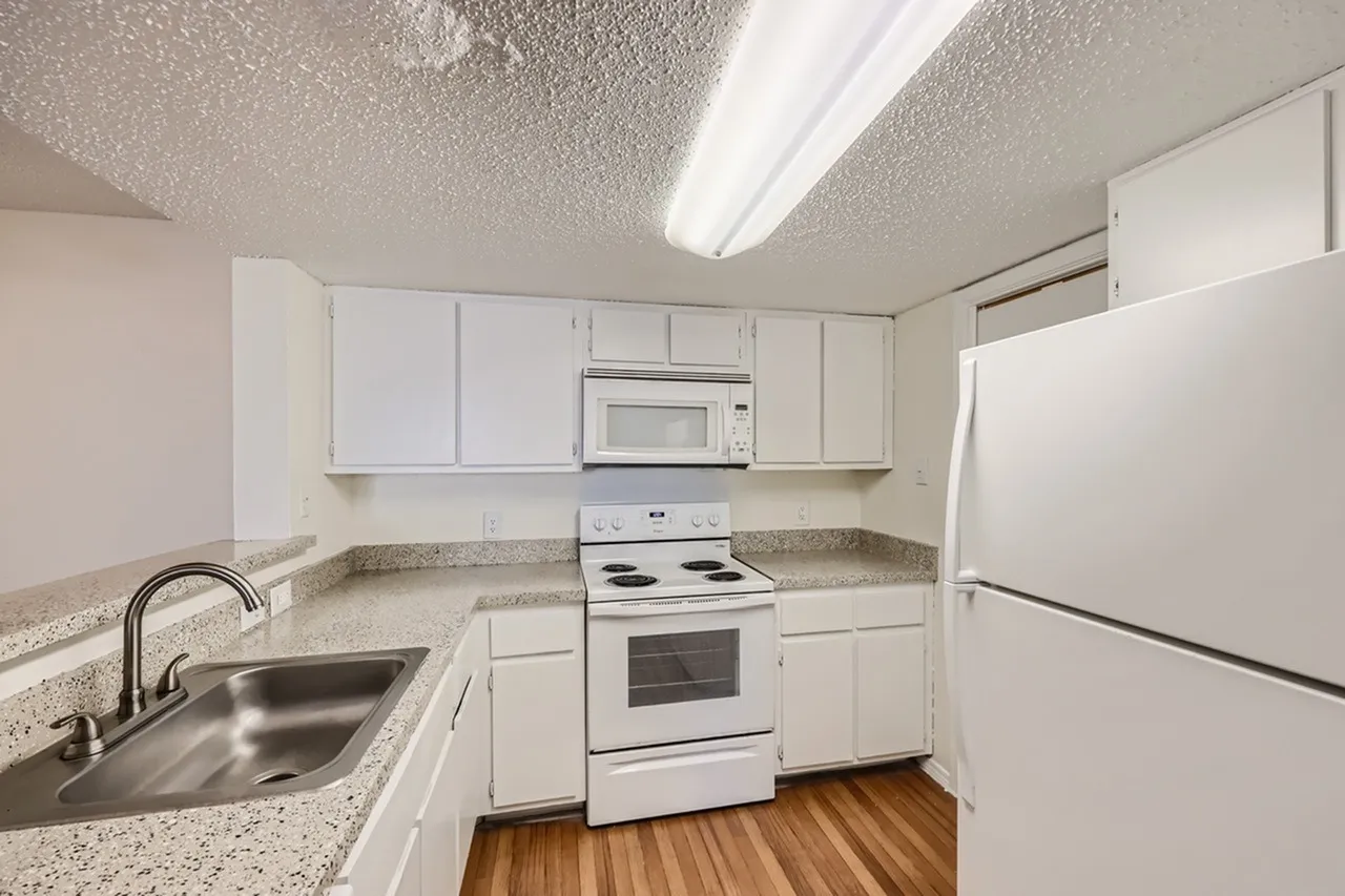 Kitchen, white shaker cabinetry, speckled quartz countertops, stainless appliances, wood-style plank flooring