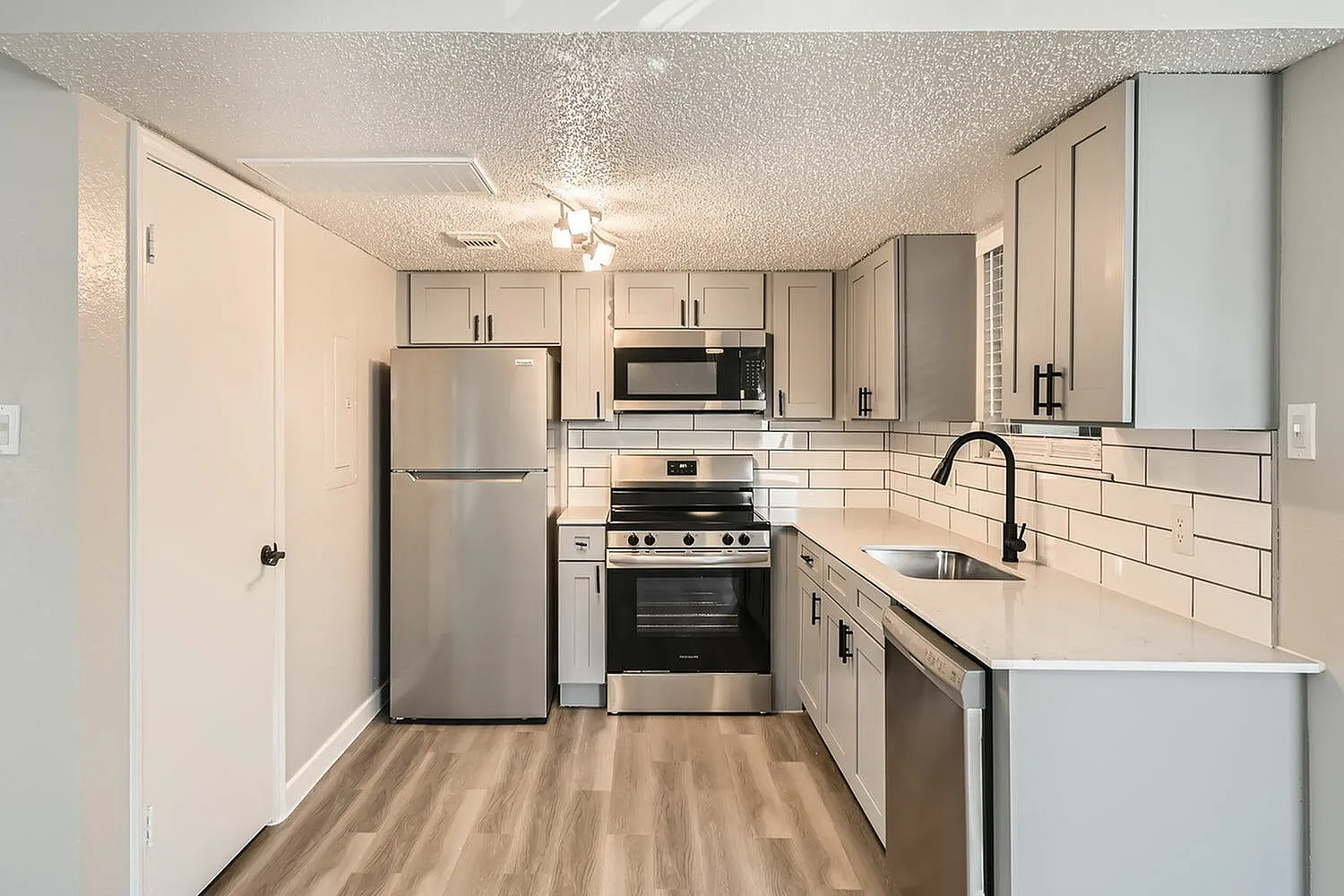 Kitchen, white shaker cabinetry, subway tile backsplash, stainless steel appliances, quartz countertops, wood-style plank flooring