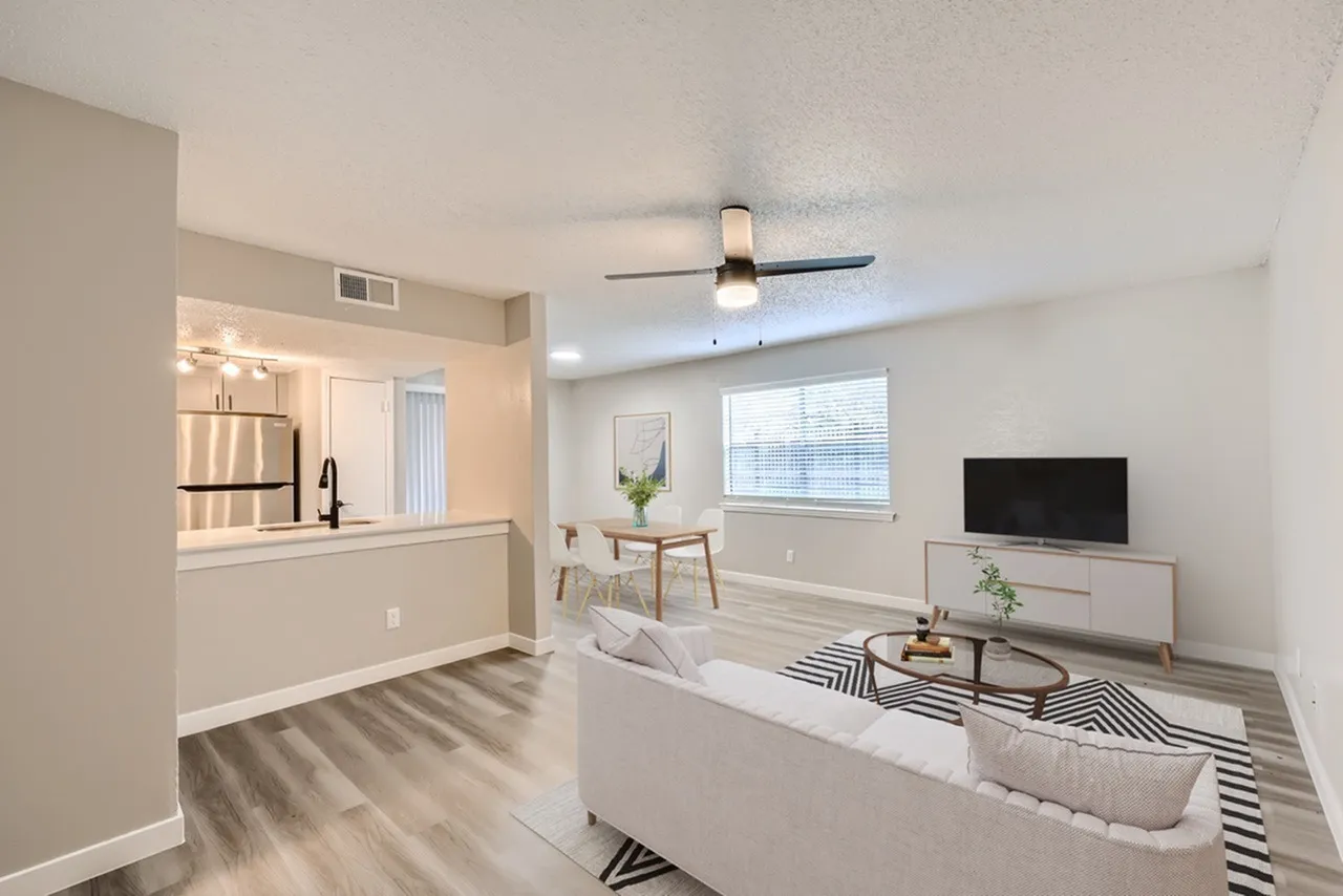 Open concept living and kitchen area, wood-style plank flooring, stainless appliances, ceiling fan