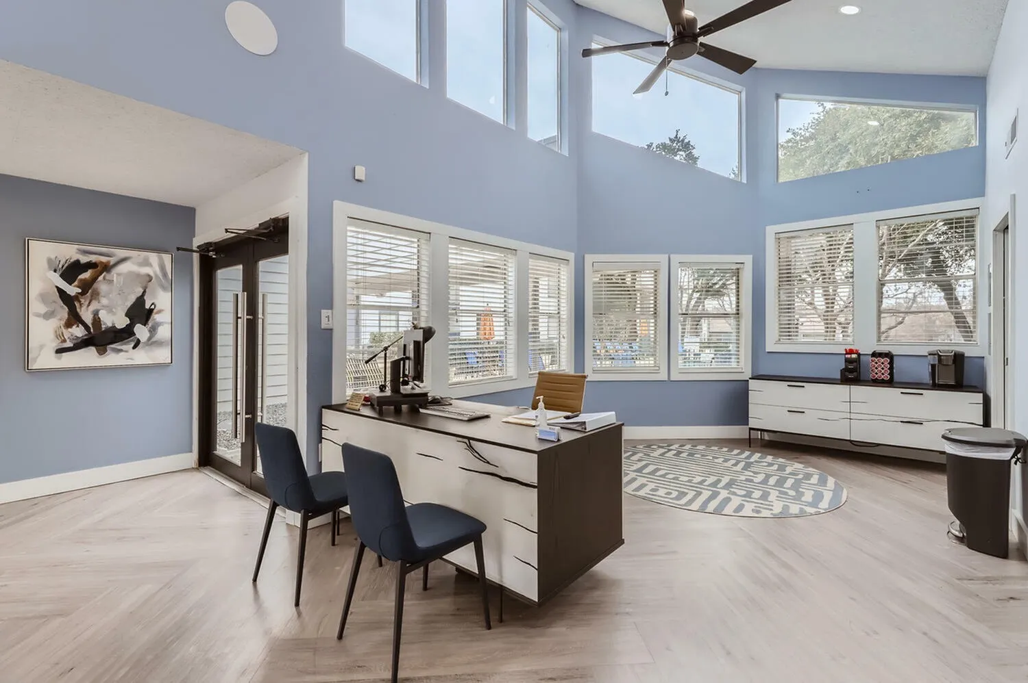 Home office, two-tone cabinetry, wood-style plank flooring, large windows with shutters, ceiling fan