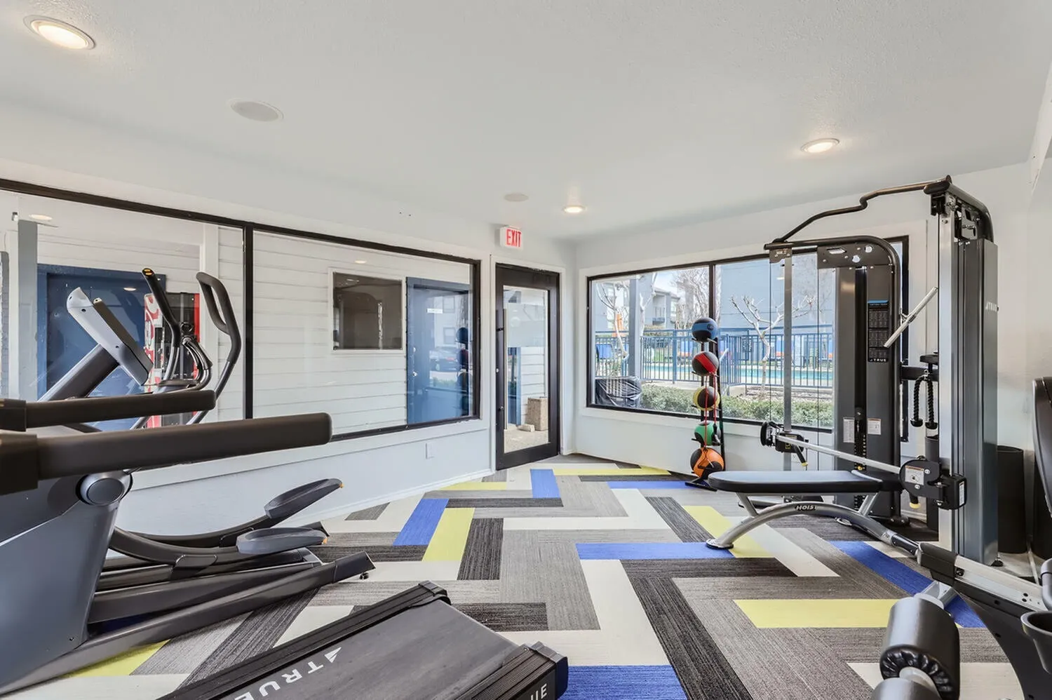 Fitness center, treadmills, weight machine, wood-style plank flooring, large windows