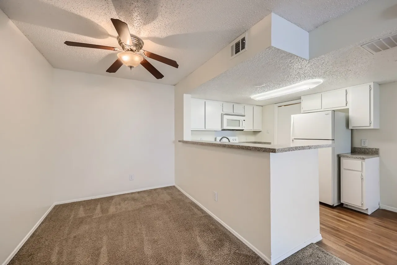 Dining area with wood-style plank flooring, ceiling fan, white cabinetry, stainless appliances