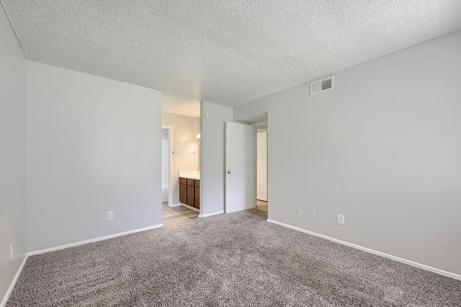 Primary bedroom, gray carpet flooring, white walls, closet doors