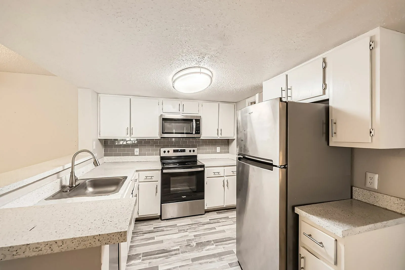 Kitchen, white shaker cabinetry, quartz countertops, stainless appliances, wood-style plank flooring
