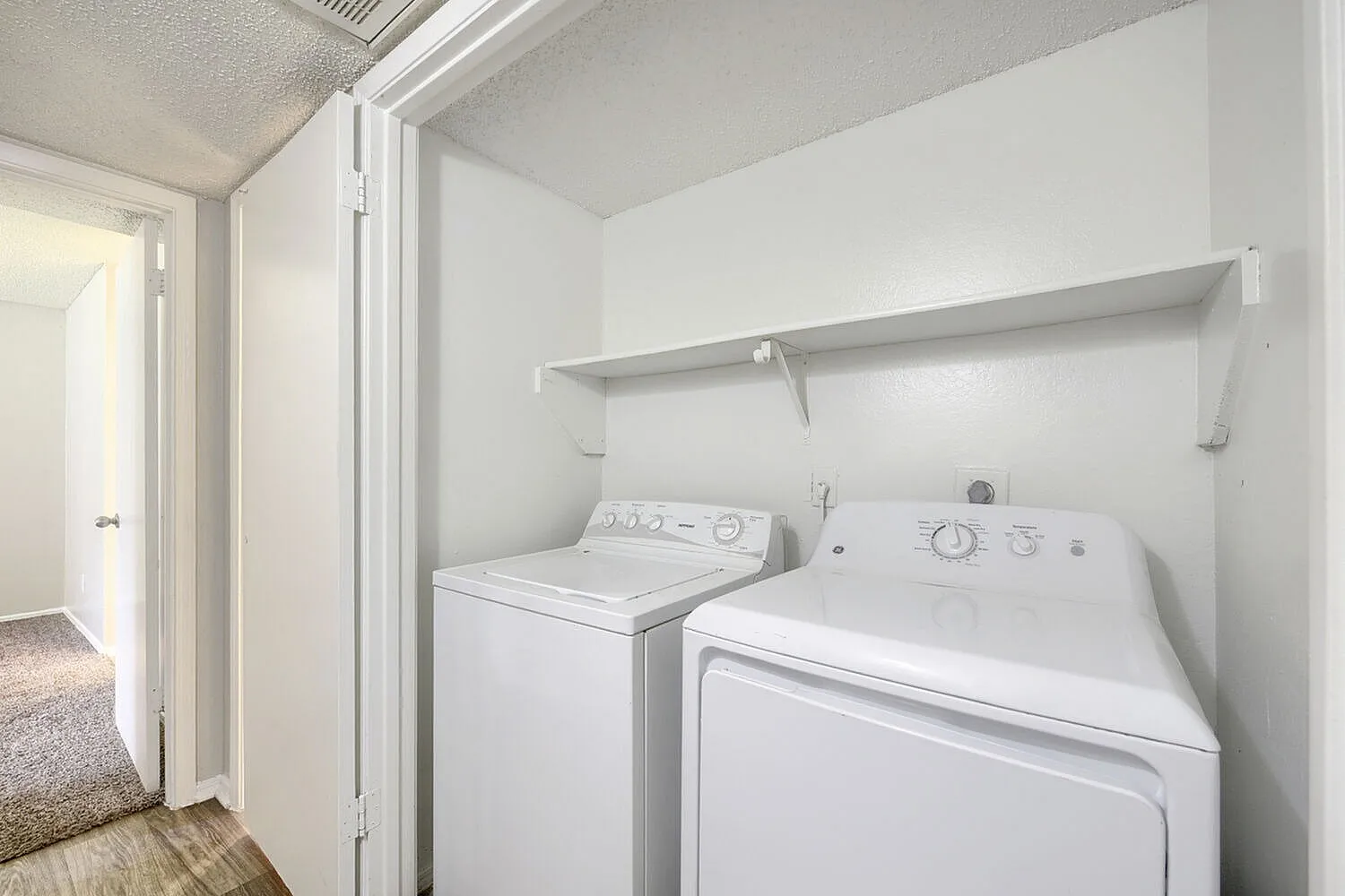 Laundry room, white washer and dryer, metal shelving, wood-style plank flooring