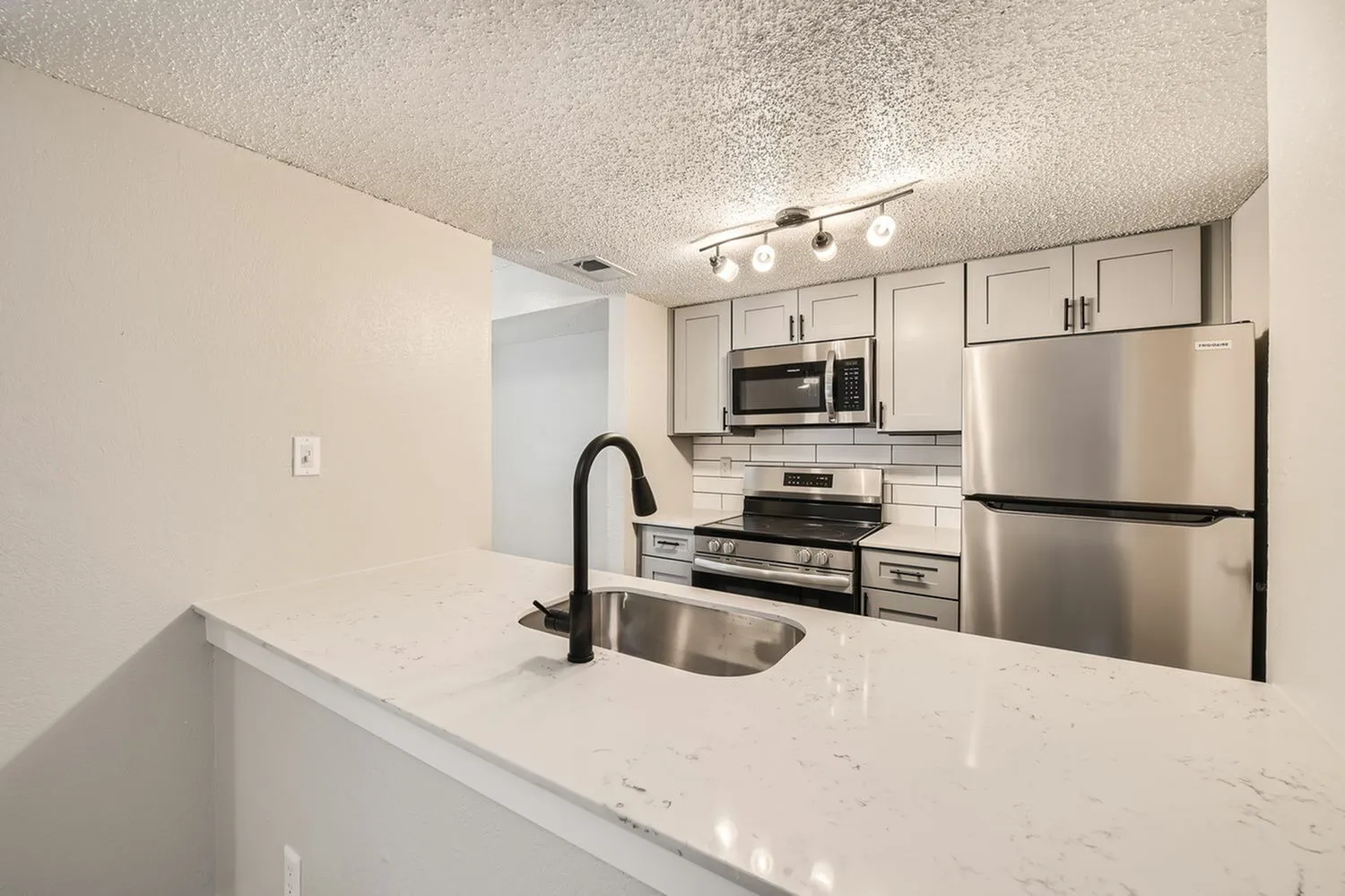 Kitchen, white quartz countertops, stainless steel appliances, light cabinetry, black faucet