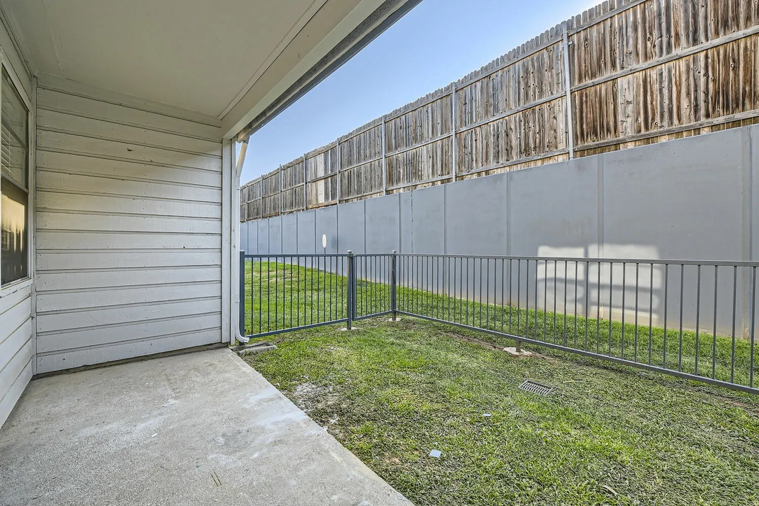 Pet area, metal fencing, concrete pad, green grass, privacy screen
