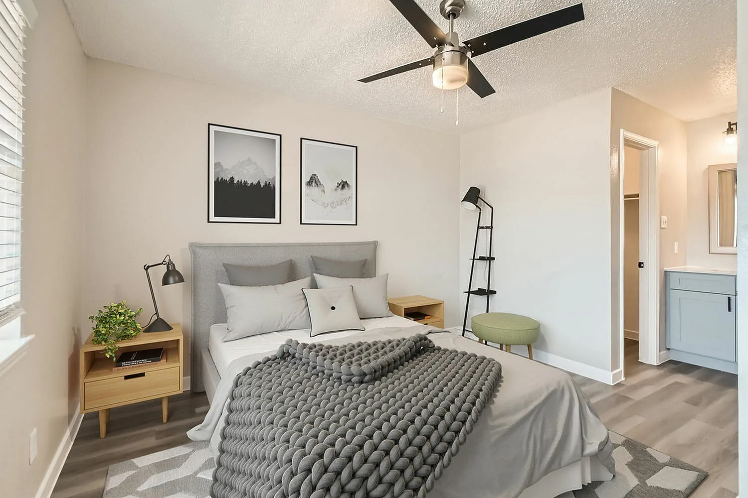 Primary bedroom, gray upholstered headboard, wood-style plank flooring, ceiling fan, framed wall art