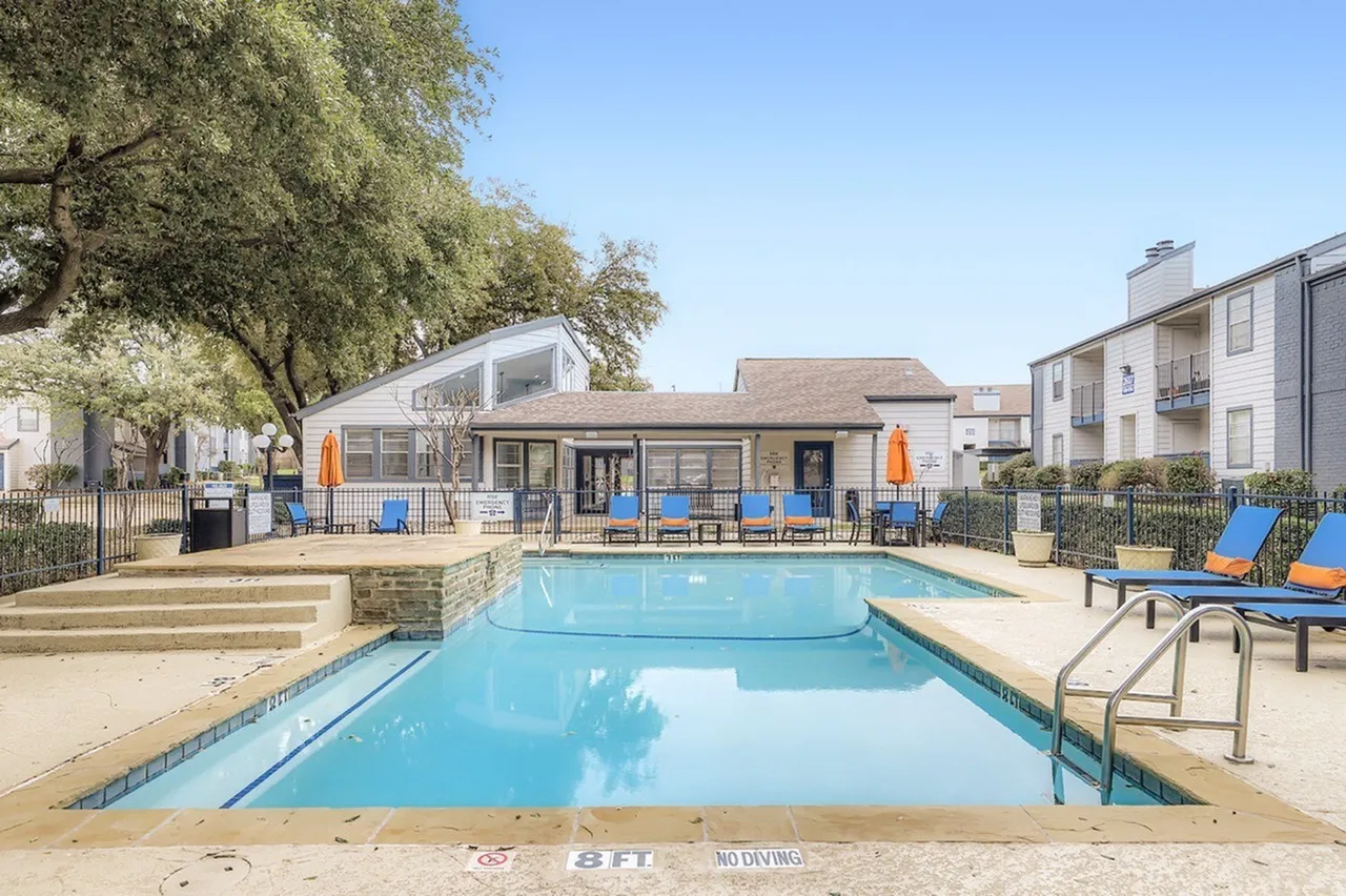 Swimming pools, lounge chairs, shade tree, community building, clear blue sky