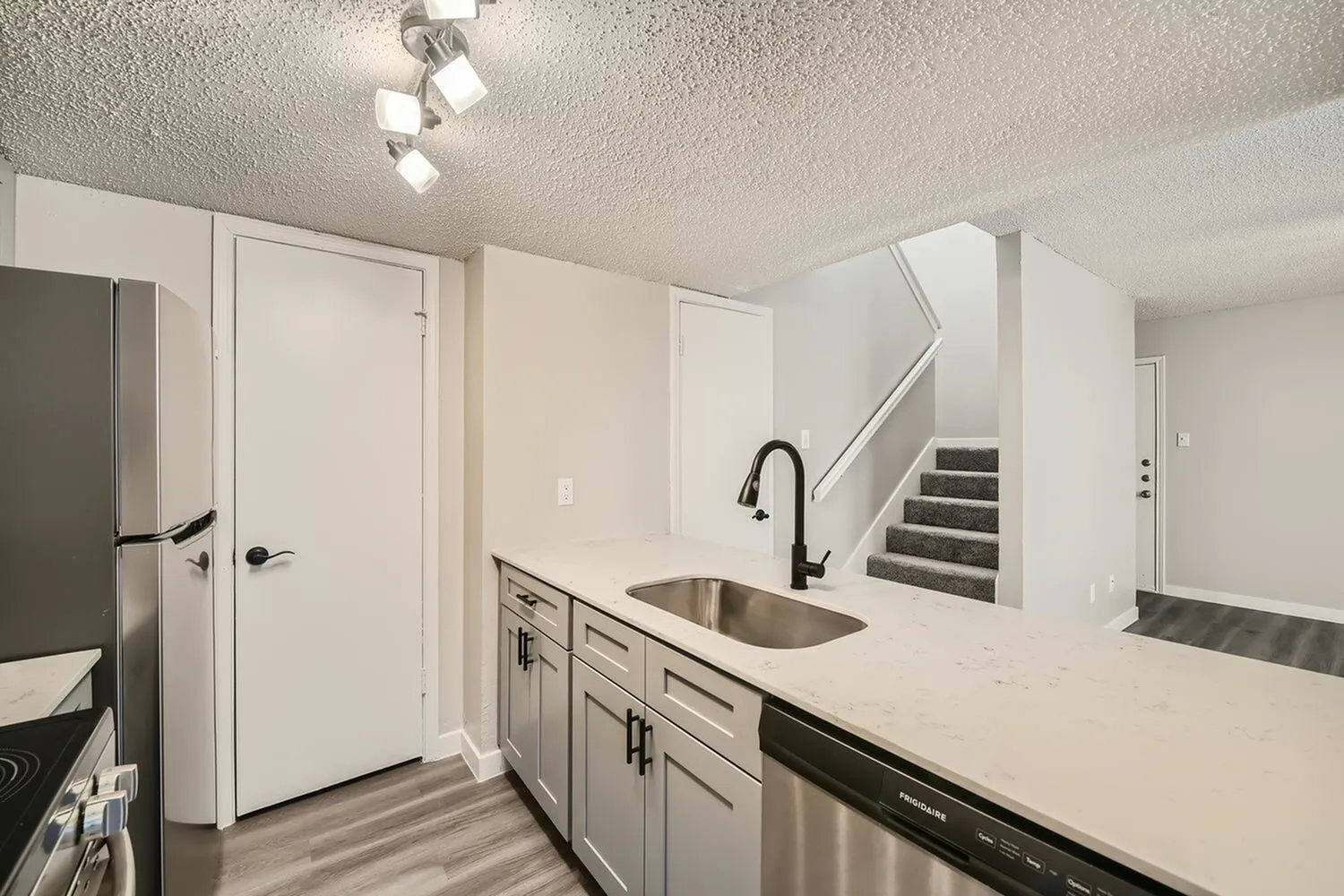Kitchen, white shaker cabinetry, quartz countertops, stainless sink, wood-style plank flooring