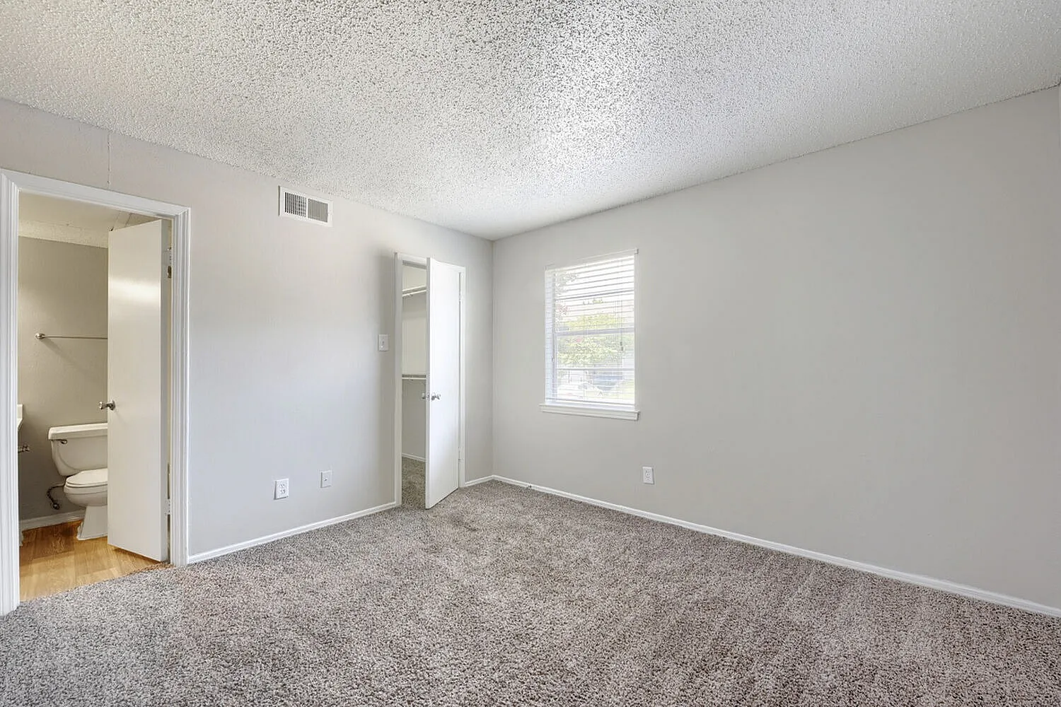 Primary bedroom, gray carpet flooring, textured ceiling, ensuite bathroom, window with natural light