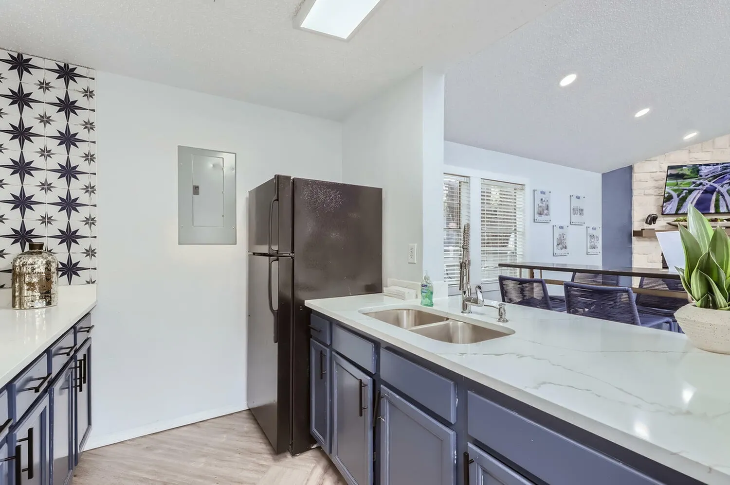 Kitchen, dark cabinetry, white quartz countertops, stainless sink, dark refrigerator, wood-style plank flooring