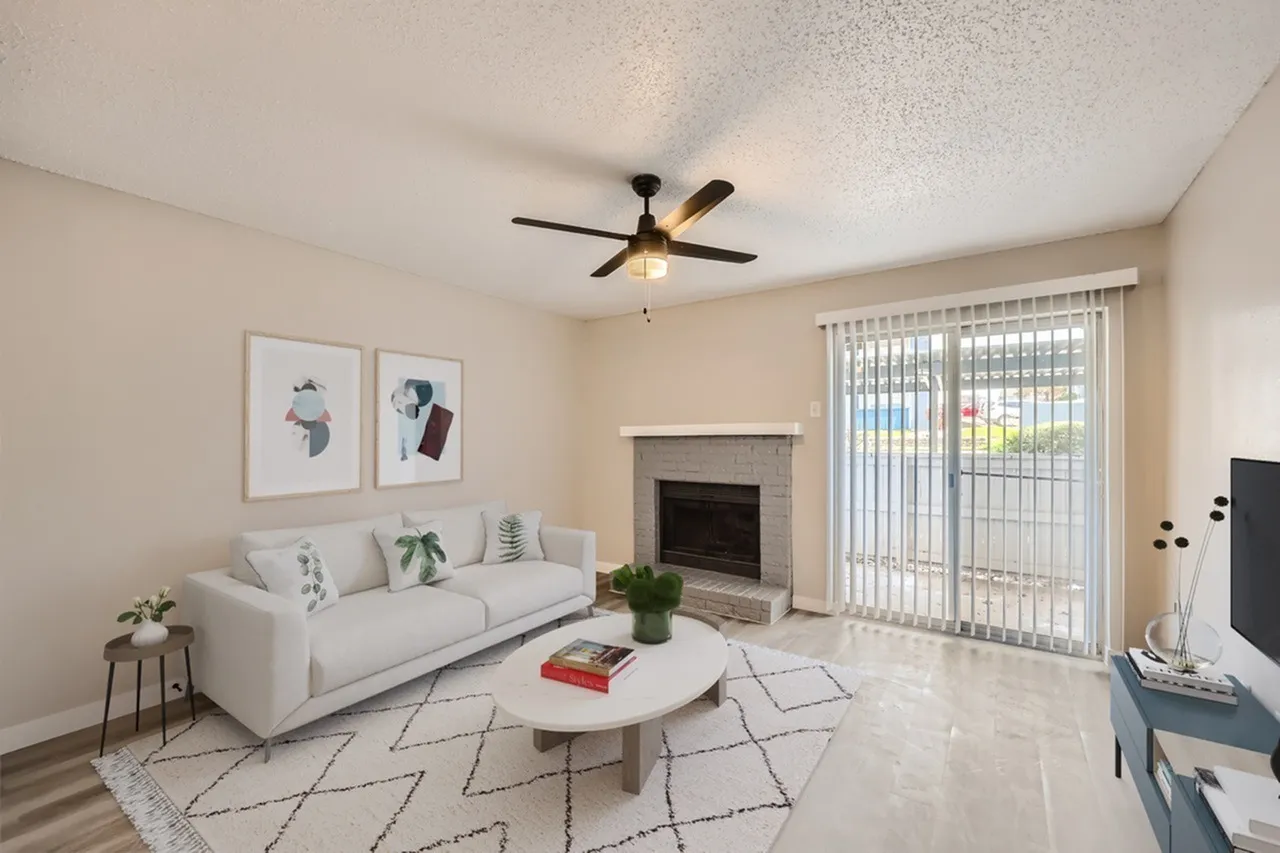 Living room with wood-style plank flooring, white sofa, fireplace, ceiling fan, glass patio doors