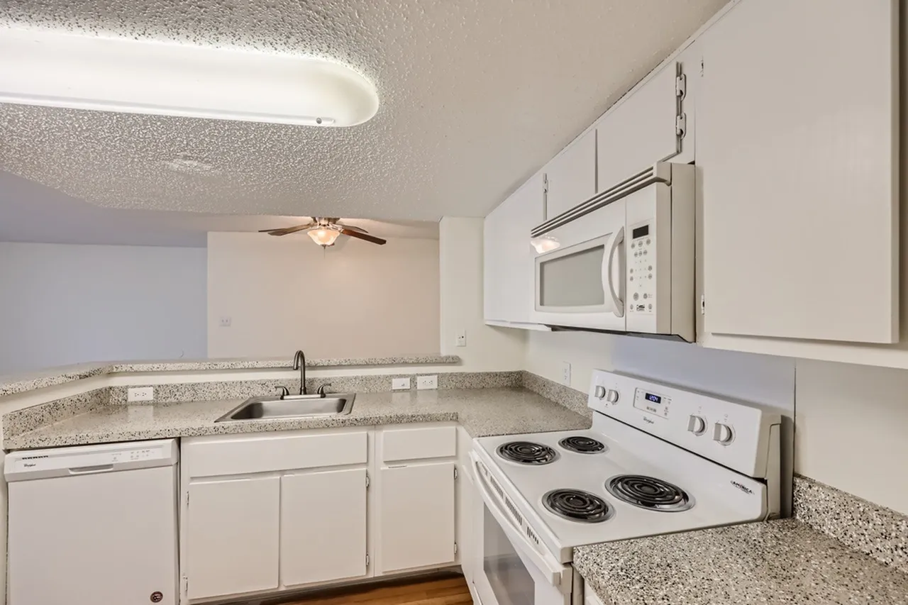 Kitchen, white shaker cabinetry, gray granite countertops, white appliances, wood-style plank flooring