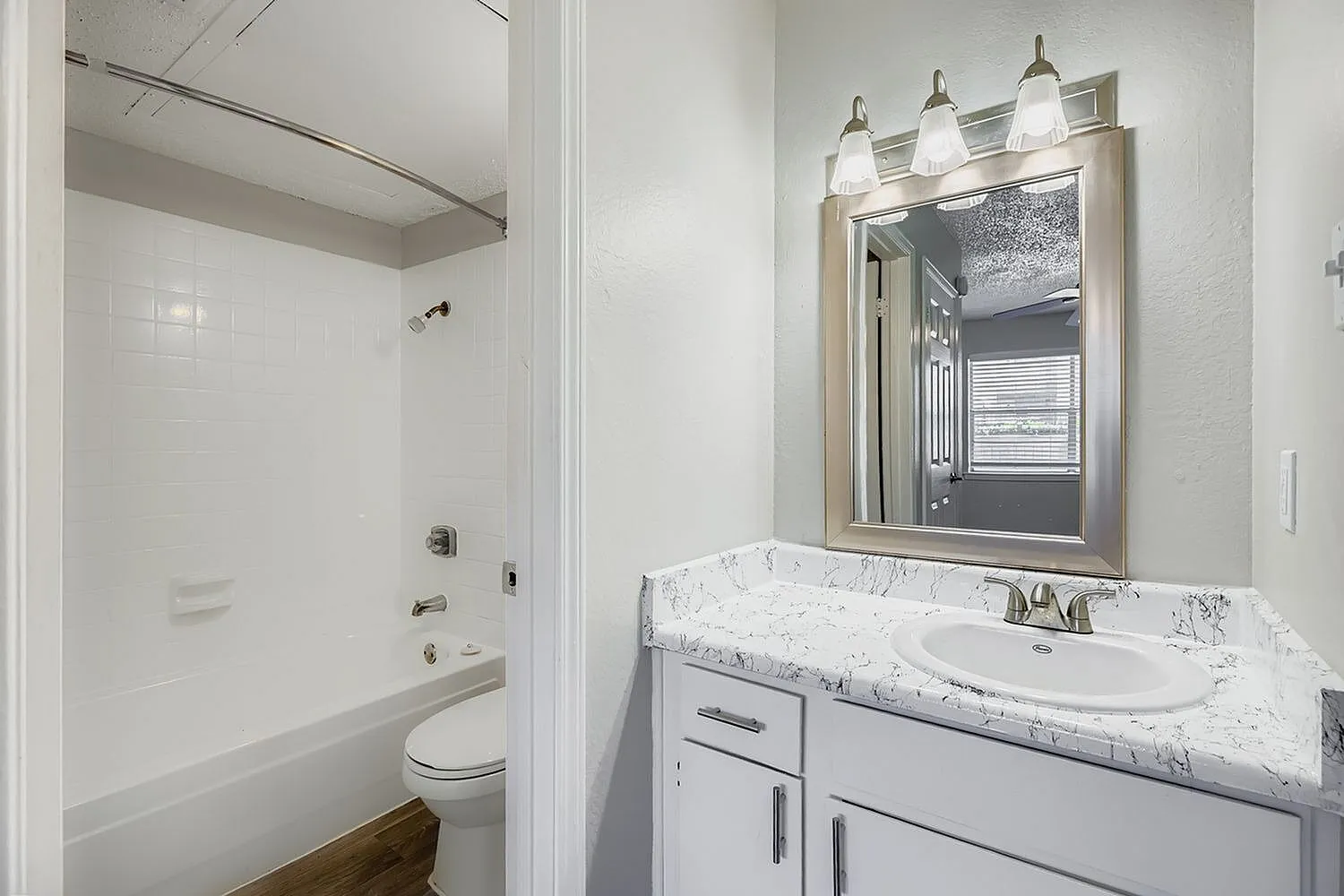 Bathroom, white marble countertops, gray vanity cabinetry, framed mirror, pendant lighting