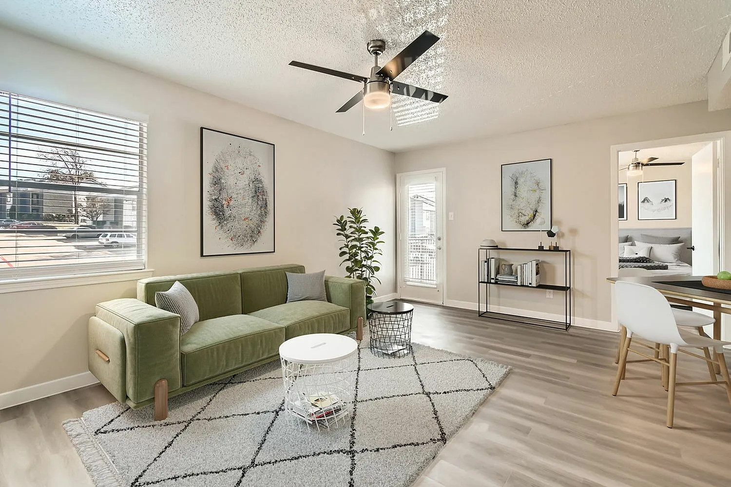 Living room, wood-style plank flooring, green curved sofa, ceiling fan, geometric area rug