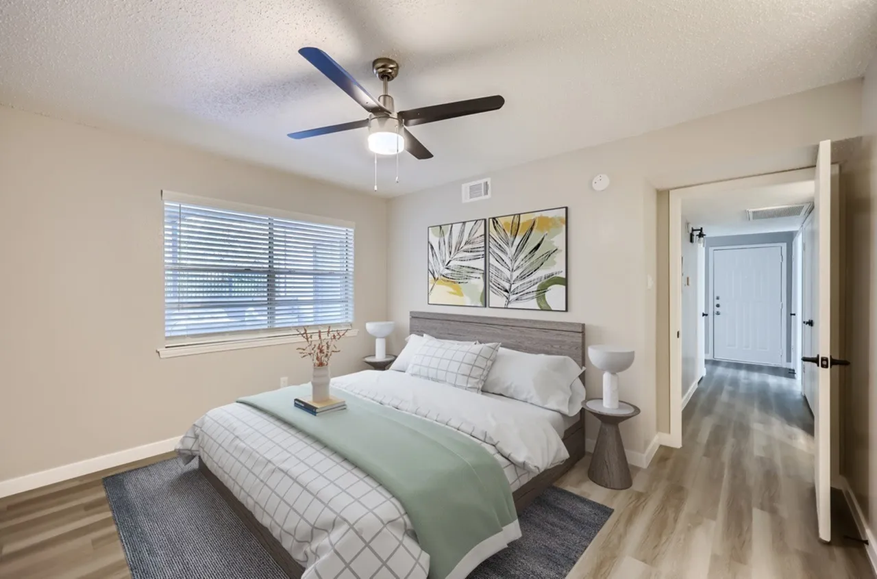 Primary bedroom, wood-style plank flooring, ceiling fan with blue and black blades, window with blinds