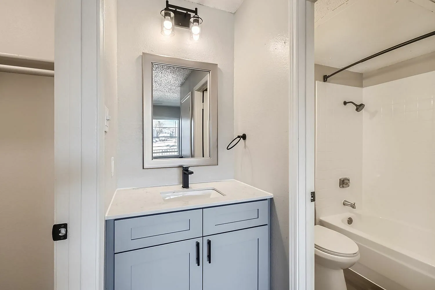 Bathroom, light blue vanity with drawers, white countertop, framed mirror, chrome fixtures