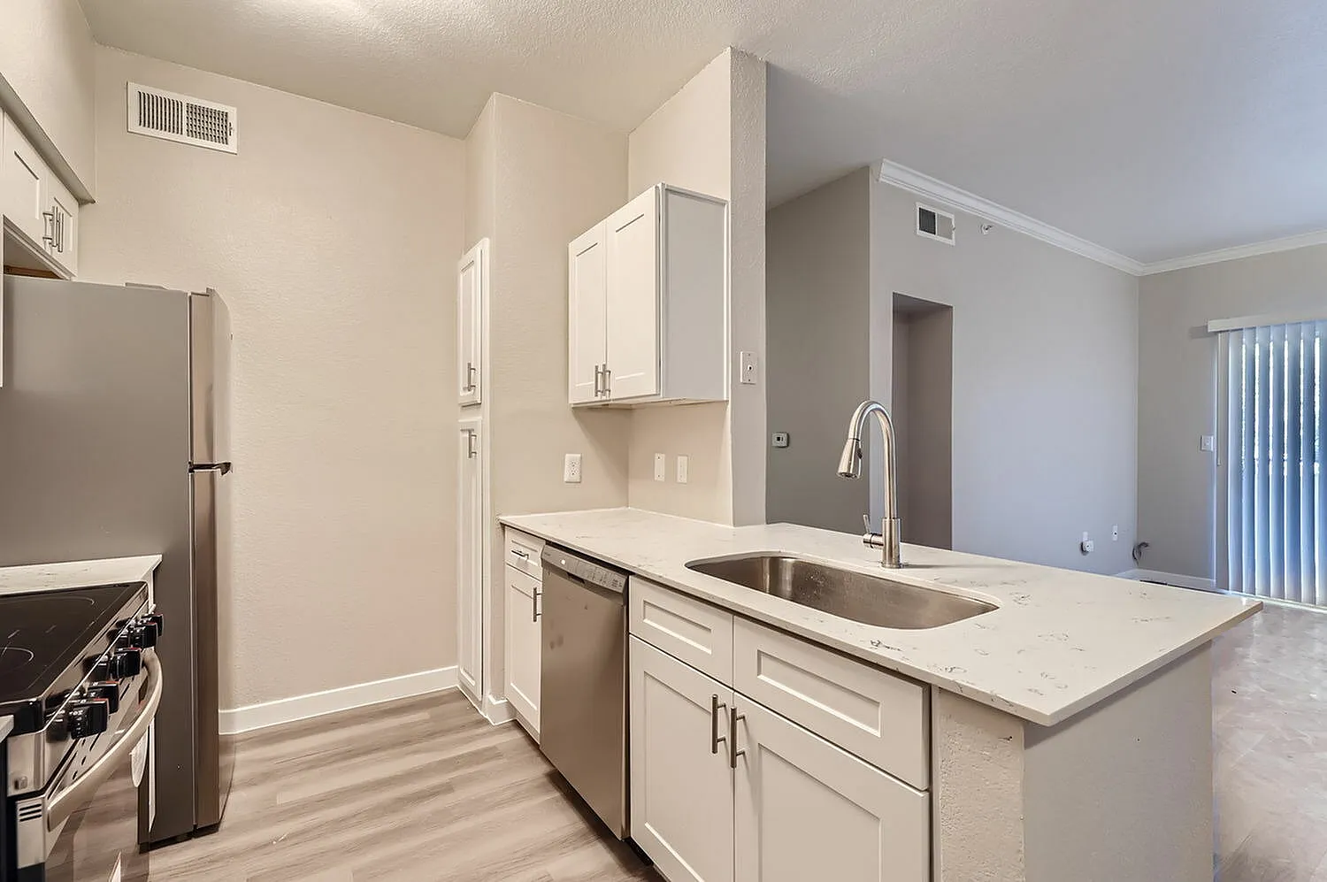 Kitchen, white shaker cabinetry, quartz countertops, stainless appliances, wood-style plank flooring