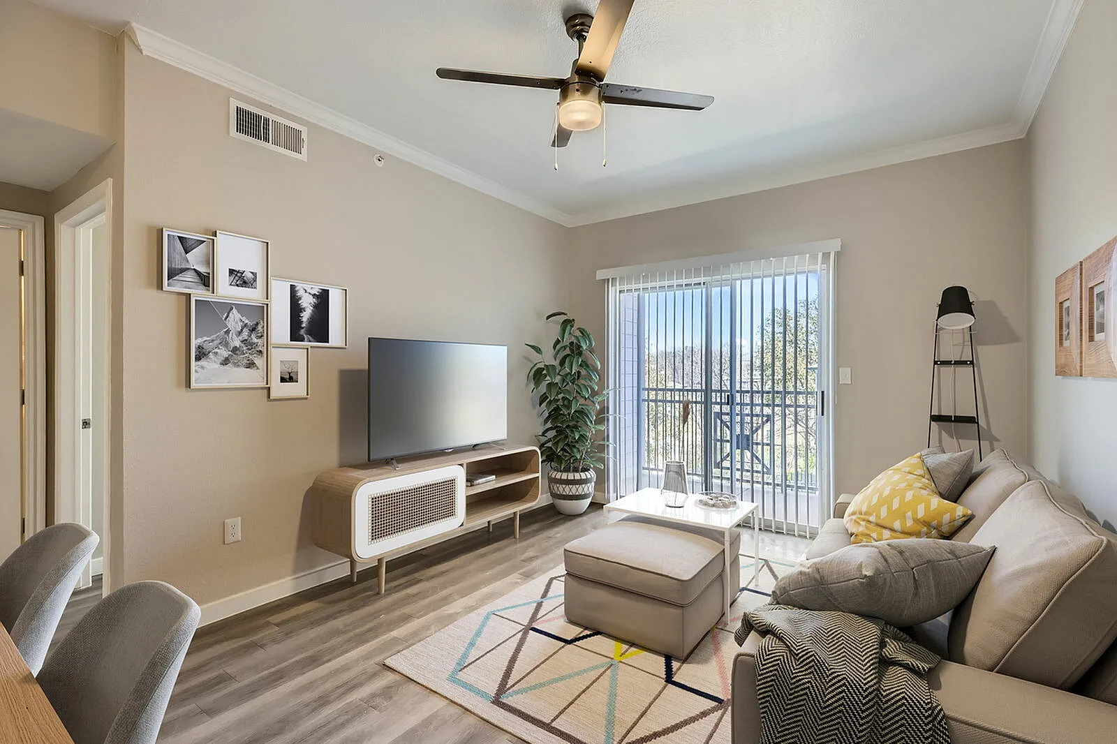 Living room, wood-style plank flooring, ceiling fan, tv mounted on stand, sofa with pillows
