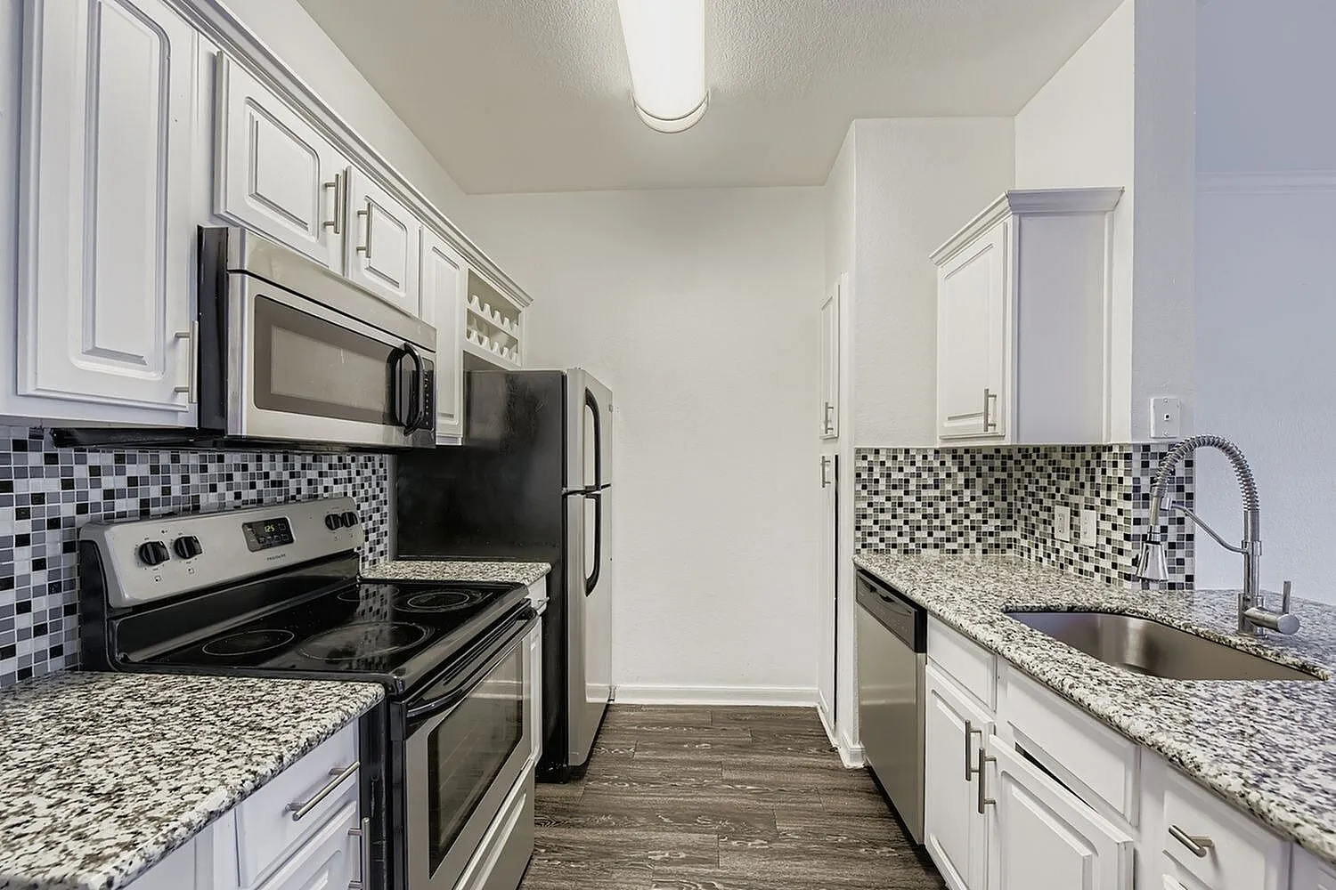 Kitchen, white shaker cabinetry, speckled quartz countertops, stainless appliances, mosaic tile backsplash, wood-style plank flooring