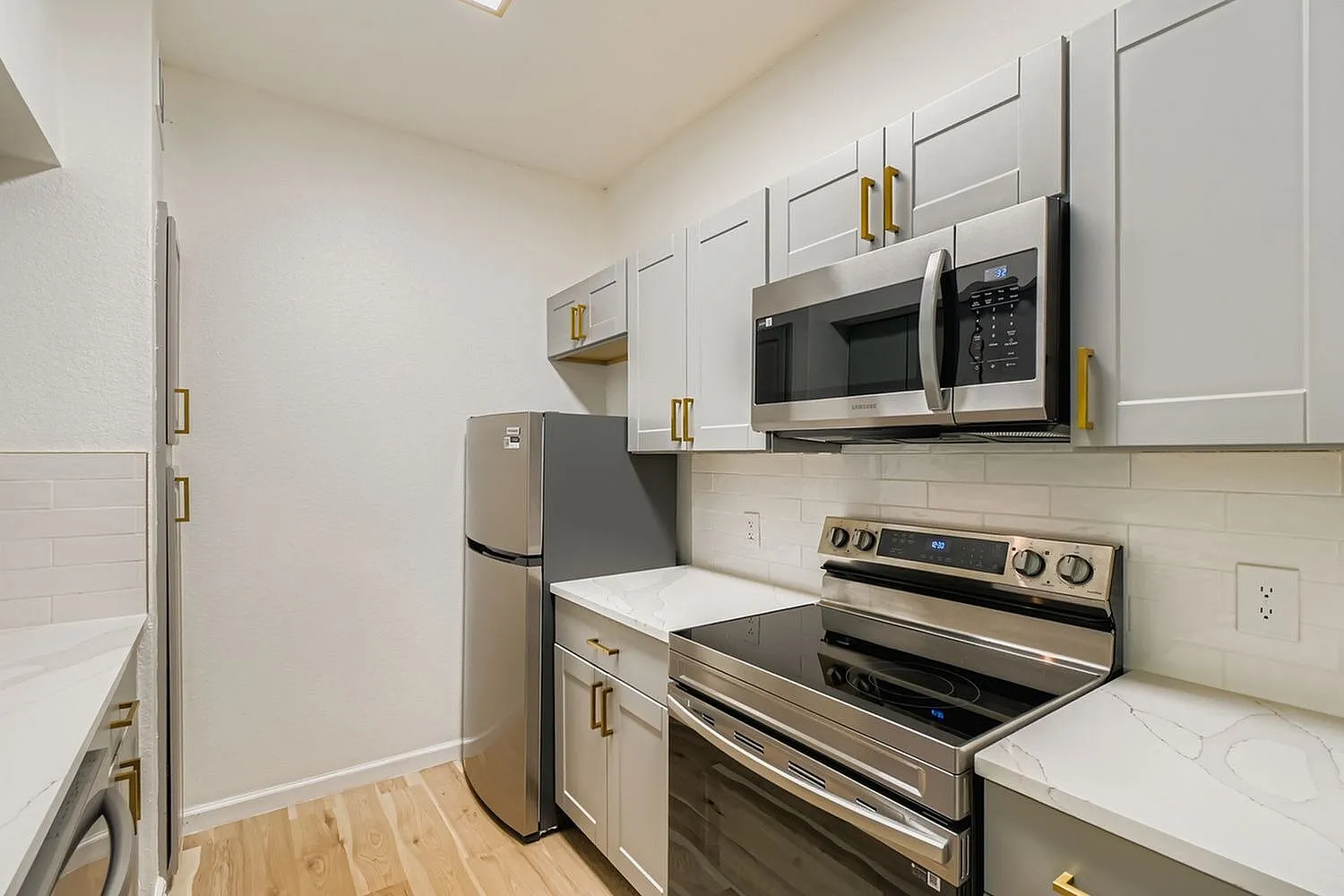 Kitchen, white shaker cabinetry, quartz countertops, stainless appliances, wood-style plank flooring
