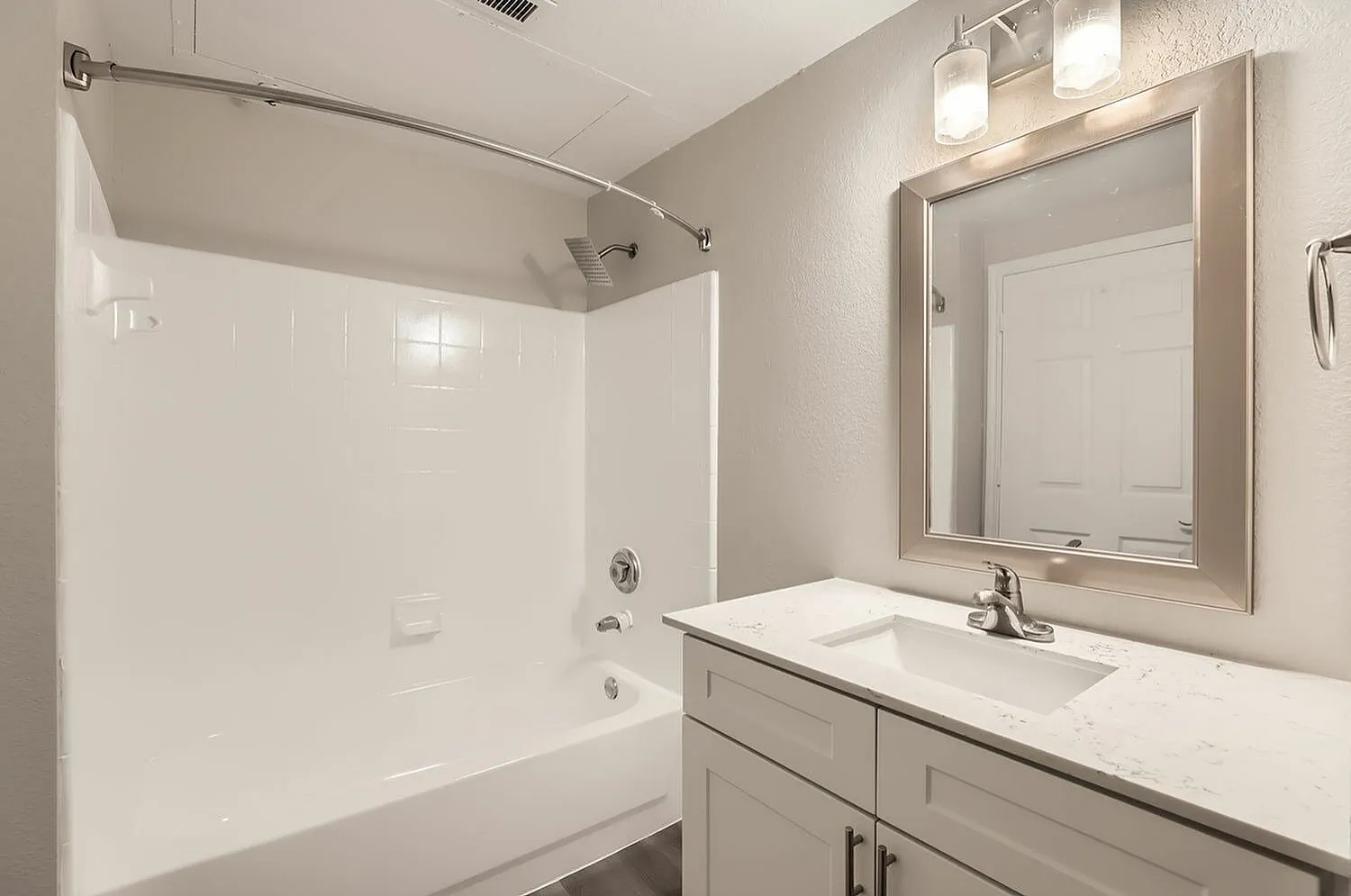 Bathroom, white quartz countertops, framed mirror, white cabinetry, tile surround