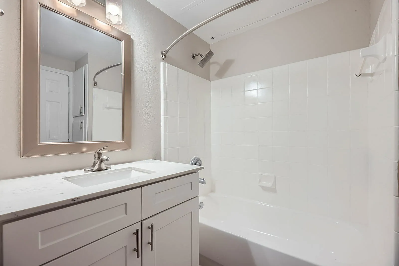 Primary bathroom, white vanity with drawers, framed mirror, white tile shower enclosure