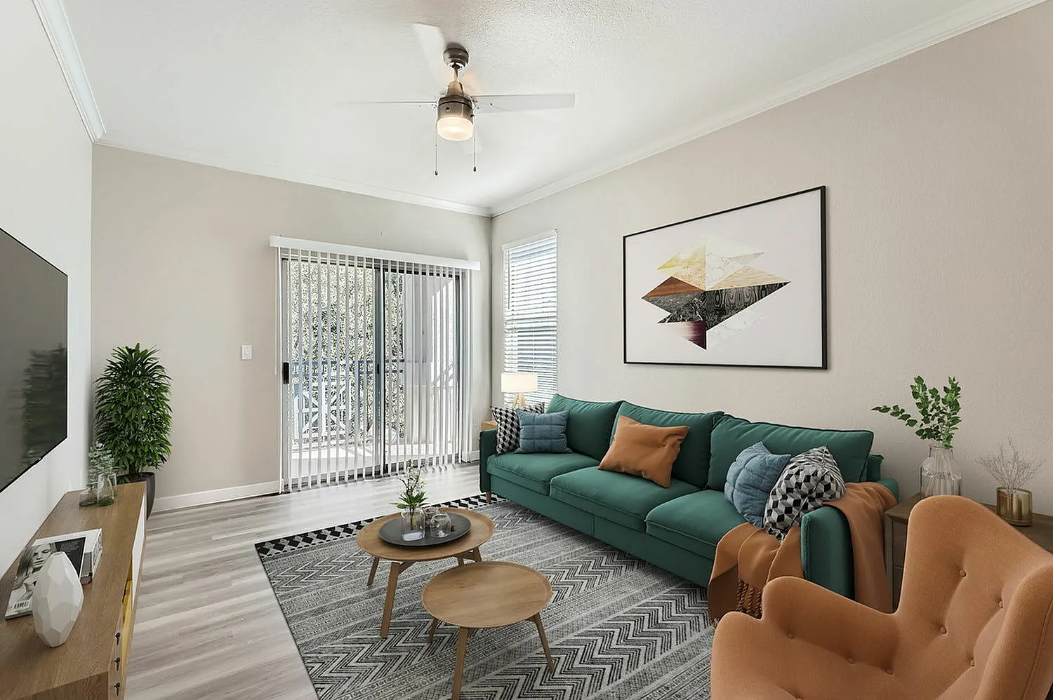 Living room, wood-style plank flooring, green sofa with throw pillows, tan accent chair, ceiling fan