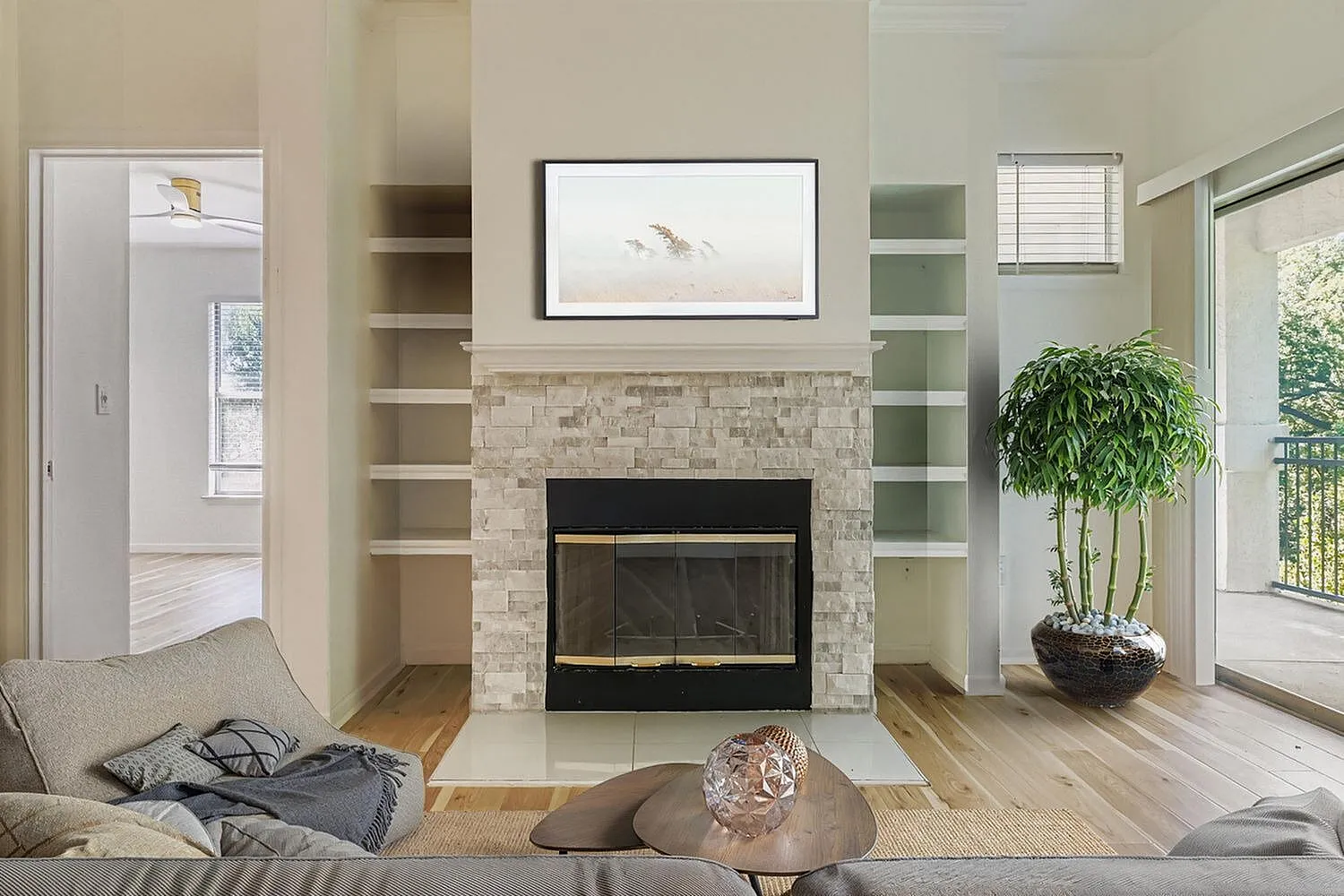 Living room, stone fireplace, wood-style plank flooring, built-in shelving, framed artwork