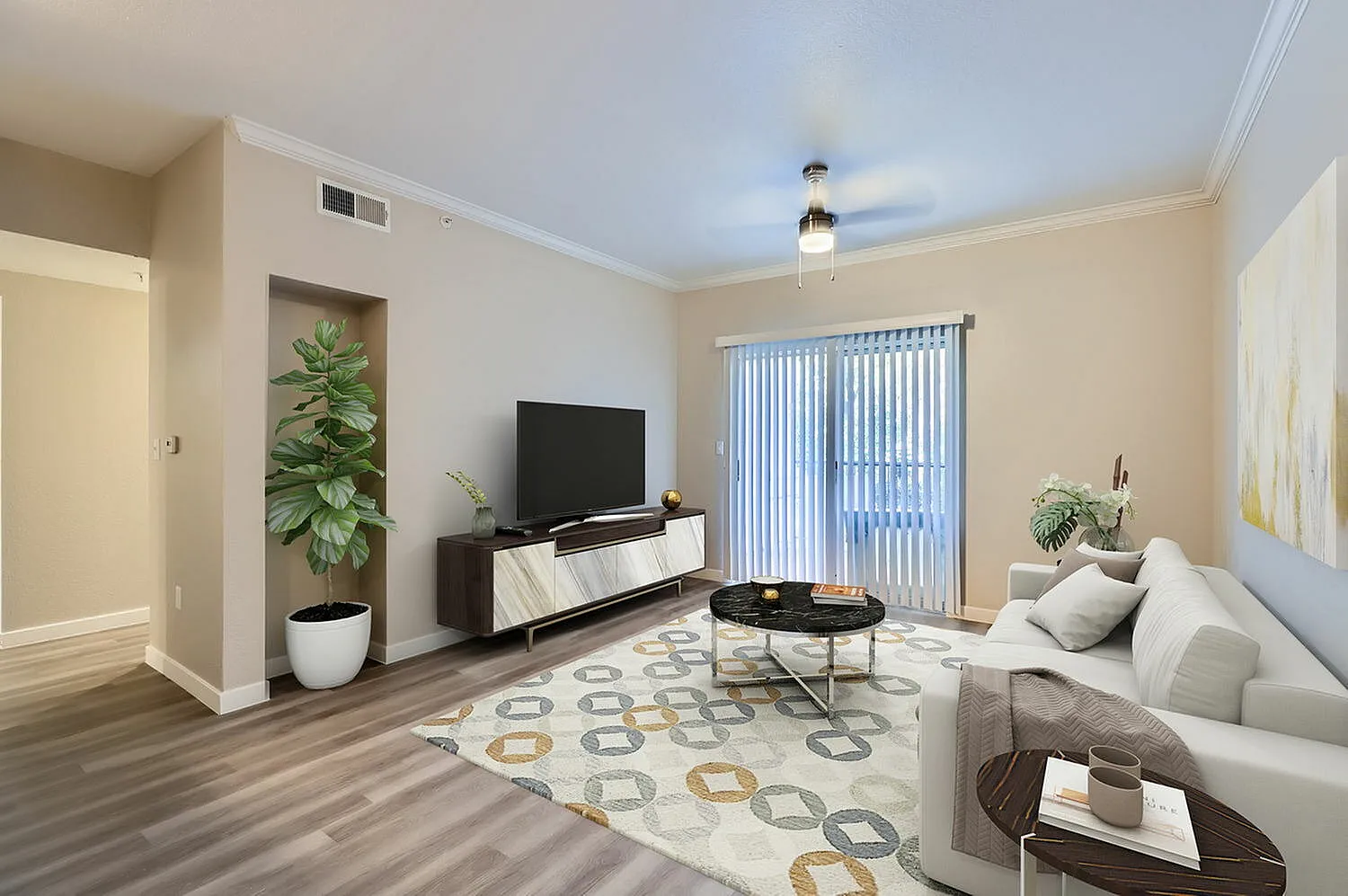 Living room with wood-style plank flooring, white sofa, entertainment center, potted plant, vertical blinds